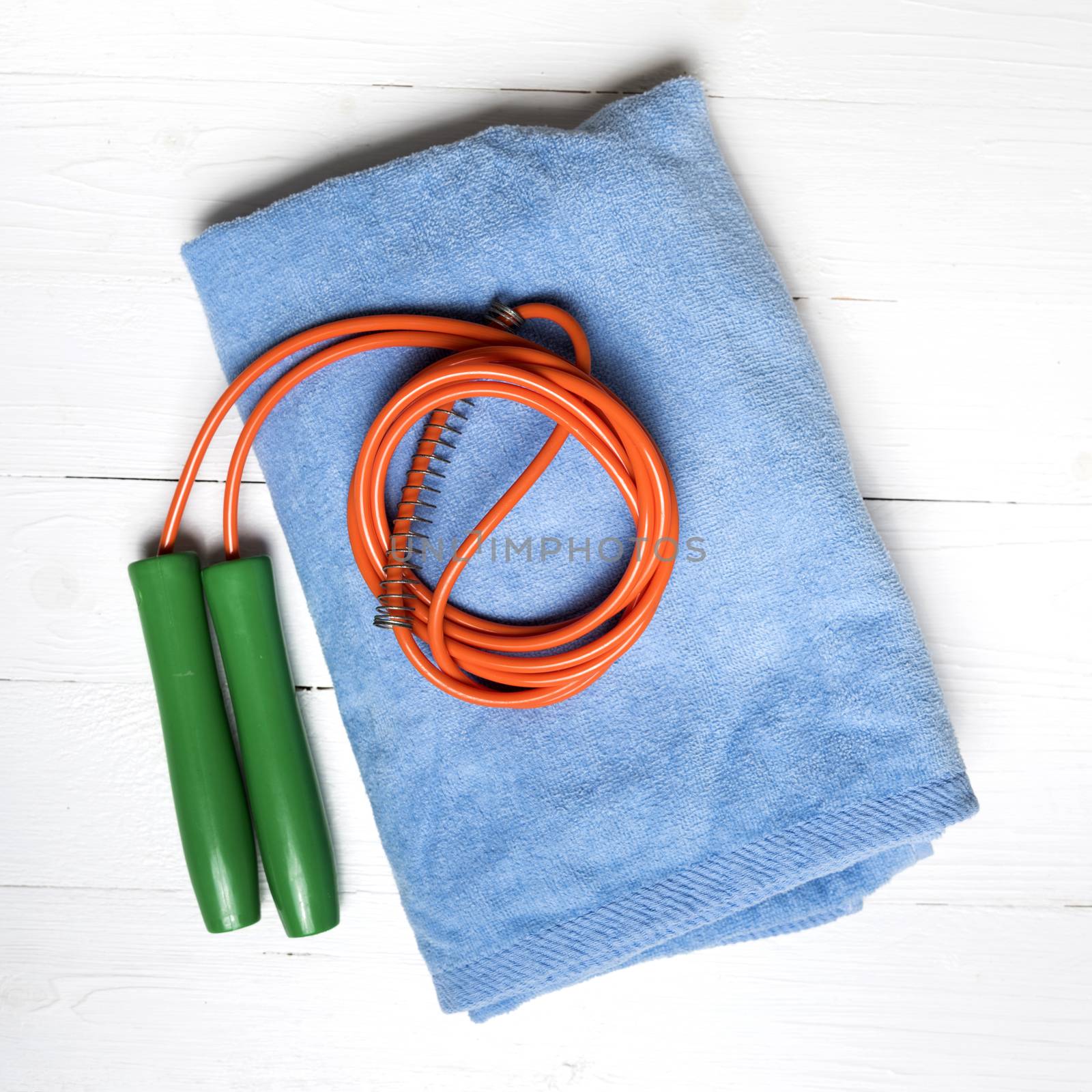 fitness equipment:blue towel,jumping rope on white wood table