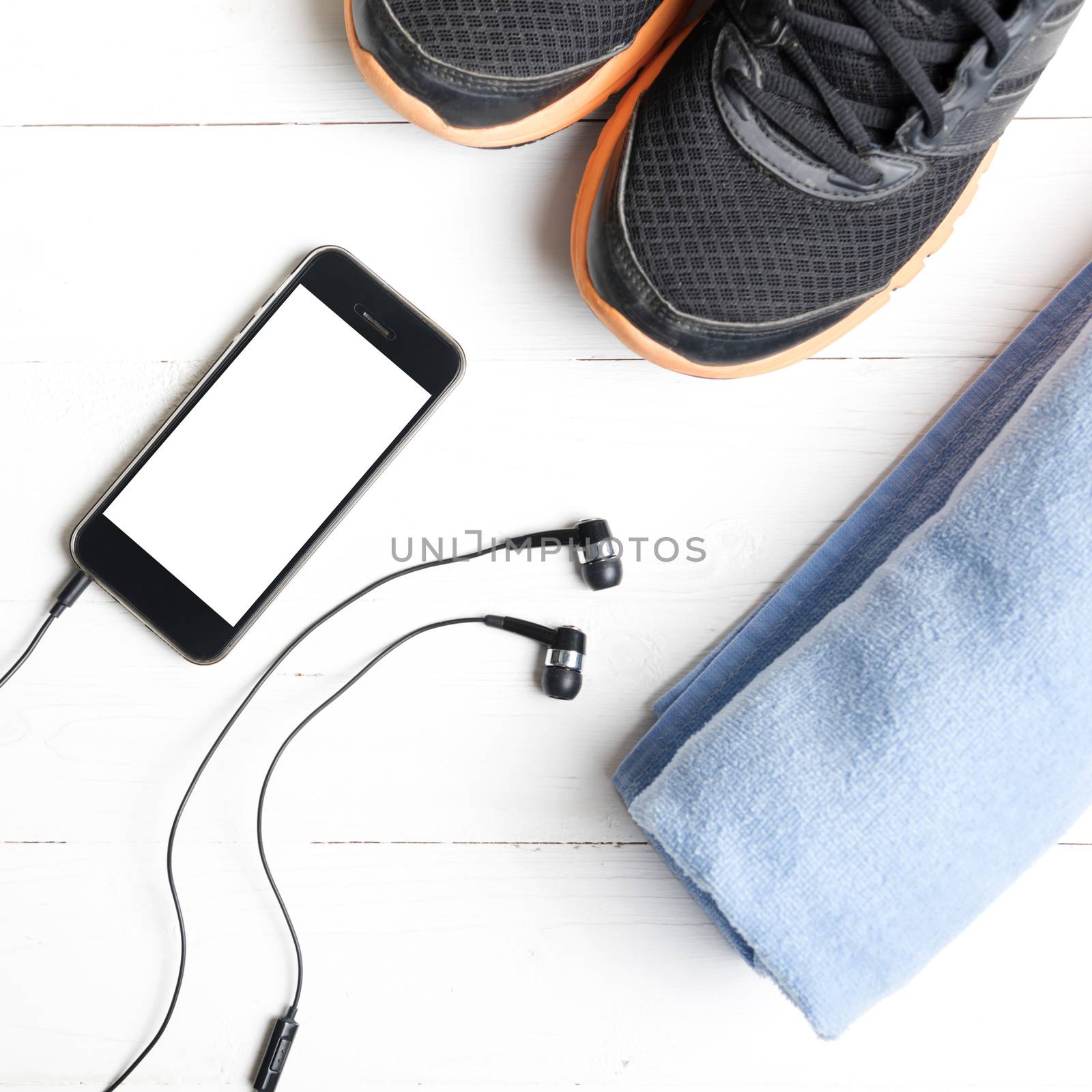 fitness equipment:running shoes,blue towel and smart phone on white wood table