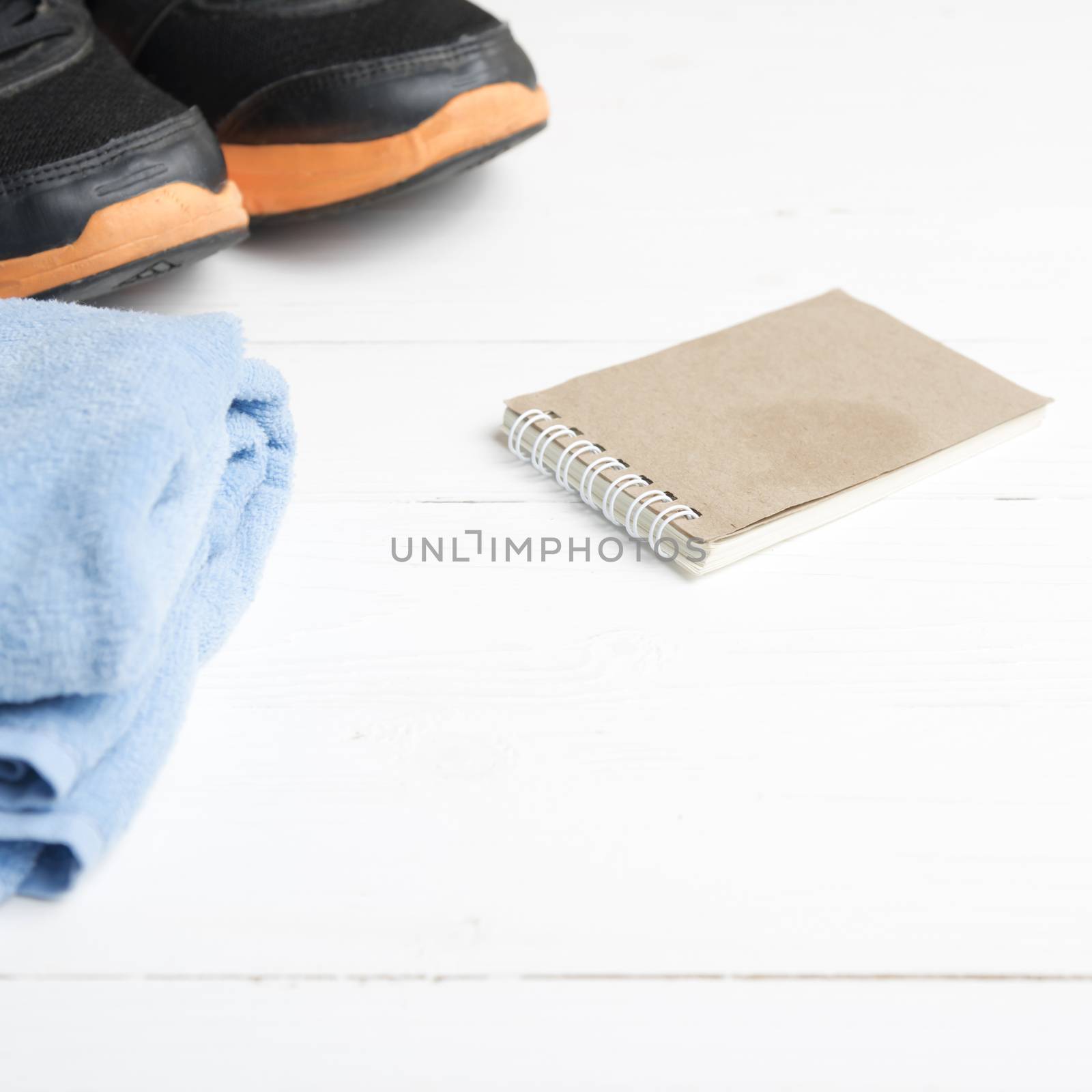 fitness equipment : running shoes,blue towel and notepad on white wood table