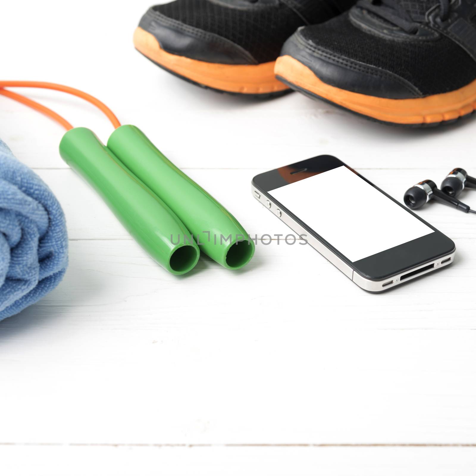 fitness equipment : running shoes,towel,jumping rope and phone on white wood table