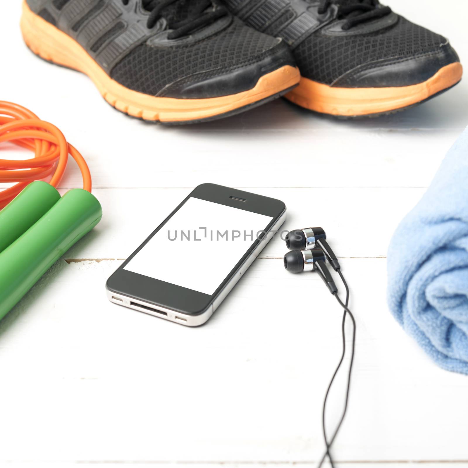 fitness equipment : running shoes,towel,jumping rope and phone on white wood table