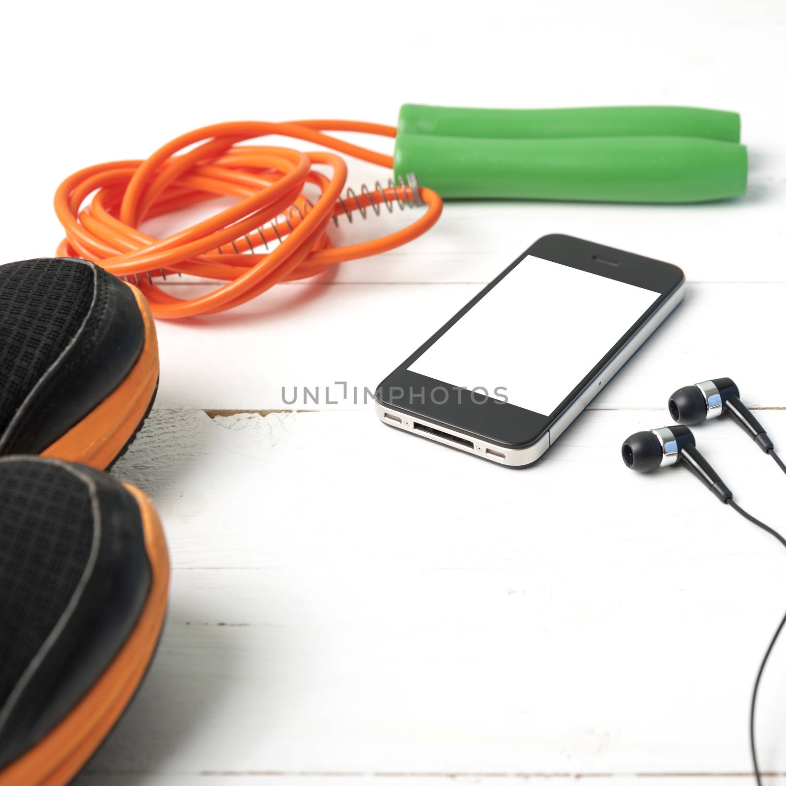 fitness equipment : running shoes,jumping rope and phone on white wood table