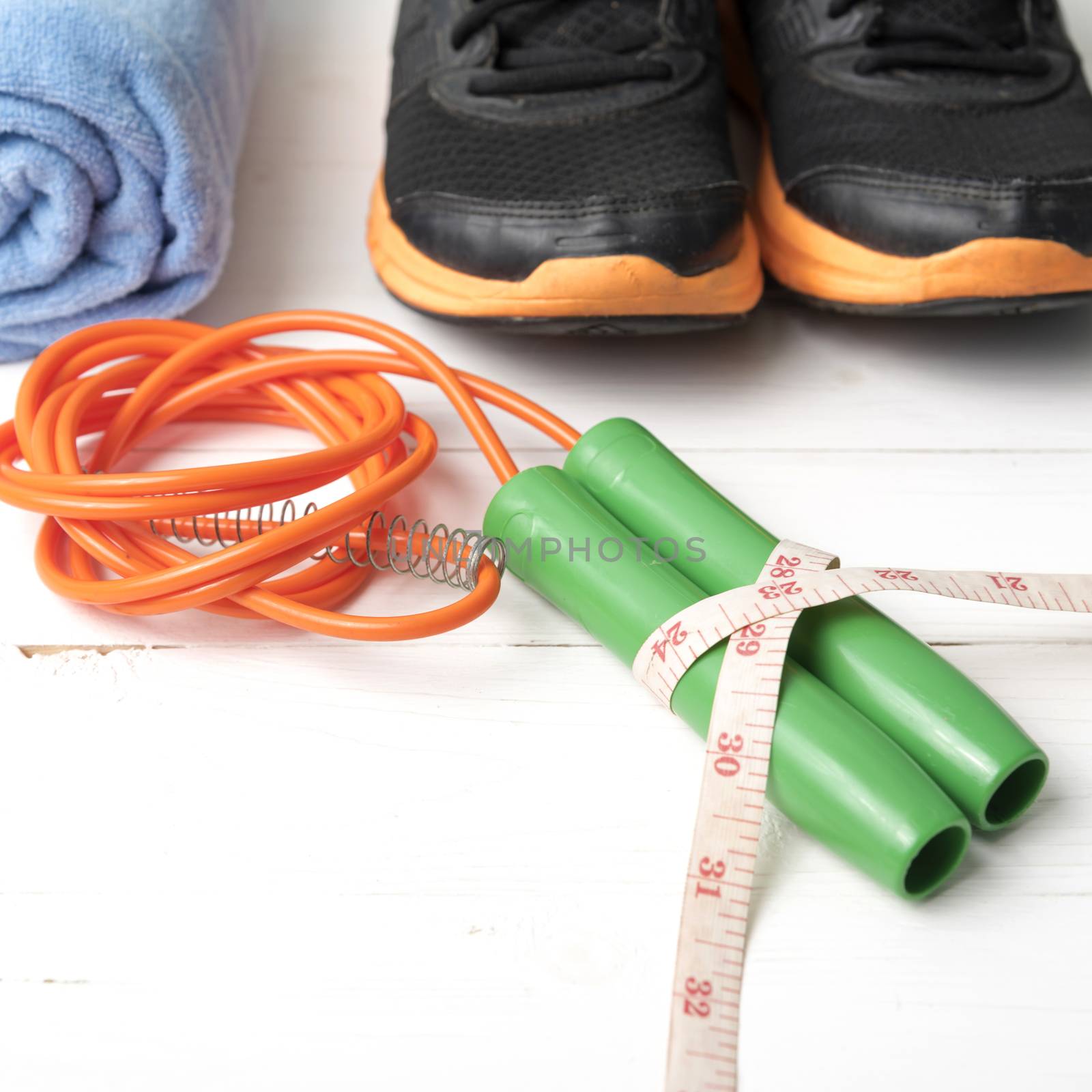 fitness equipment : running shoes,towel,jumping rope and measuring tape on white wood table