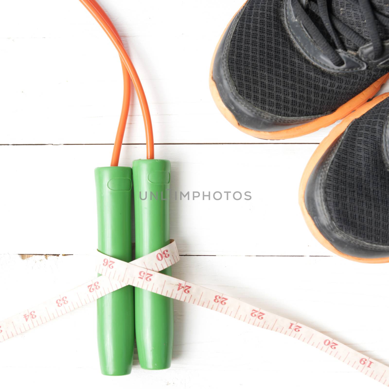 fitness equipment : running shoes,jumping rope and measuring tape on white wood table