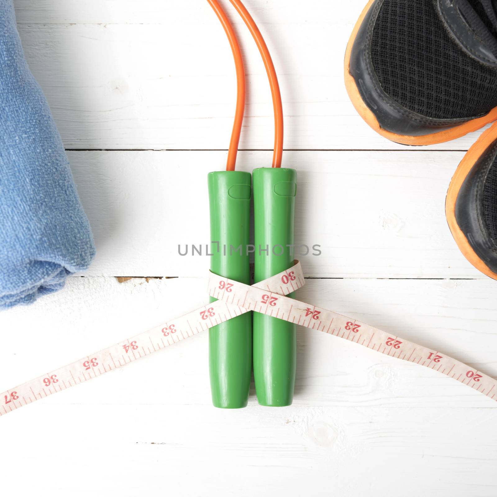 fitness equipment : running shoes,towel,jumping rope and measuring tape on white wood table