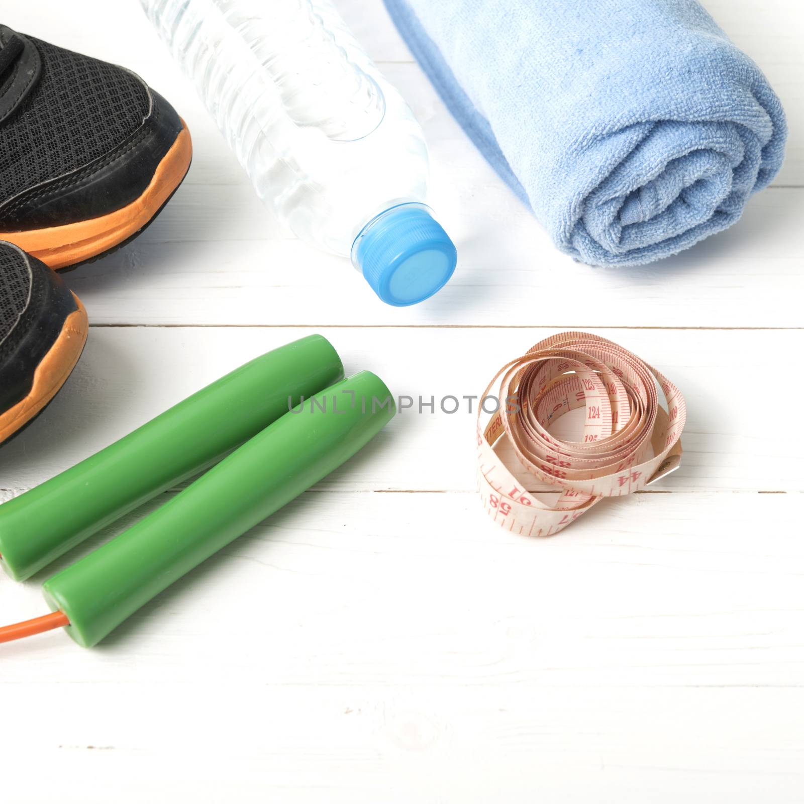 fitness equipment : running shoes,towel,jumping rope,water bottle and measuring tape on white wood table