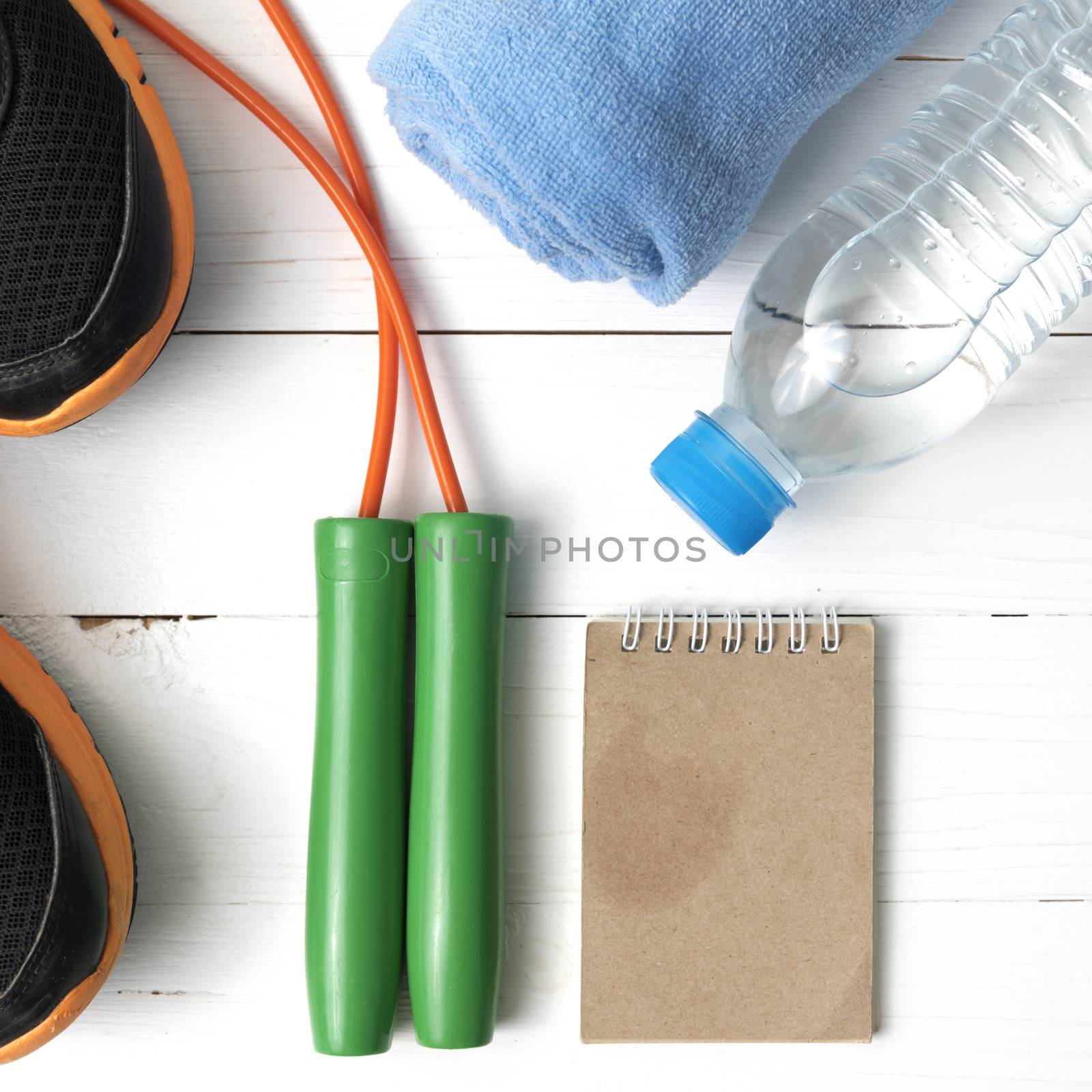 fitness equipment : running shoes,towel,jumping rope,water bottle and notepad on white wood table