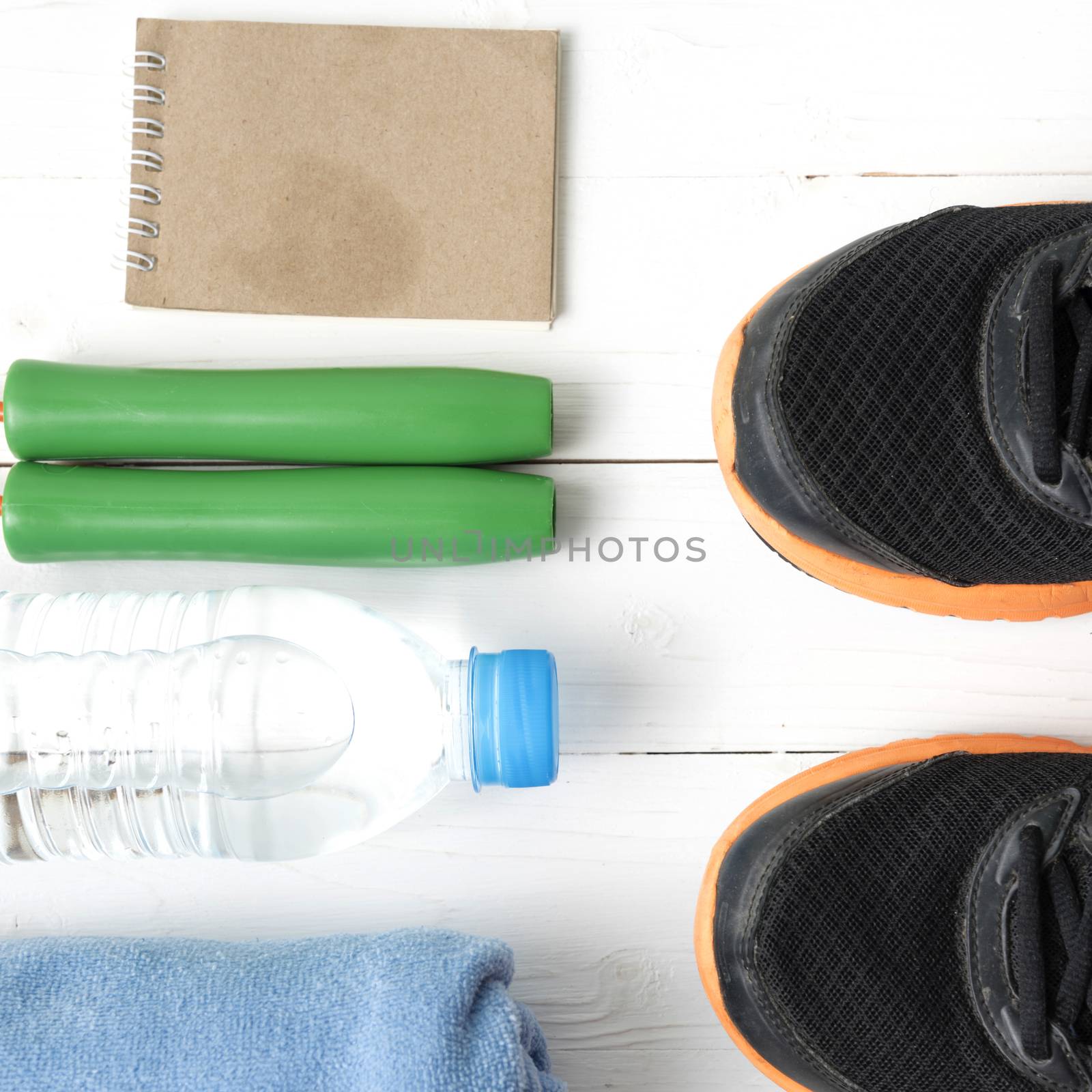 fitness equipment : running shoes,towel,jumping rope,water bottle and notepad on white wood table