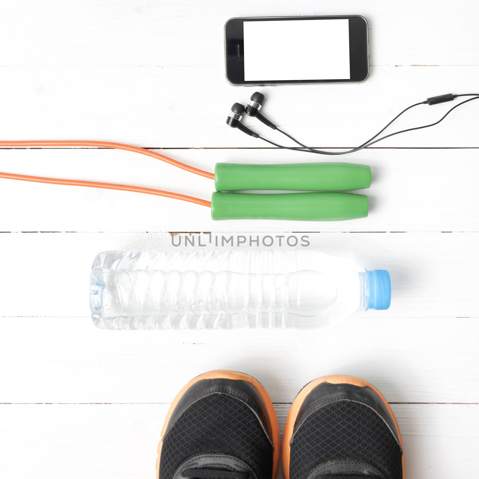 fitness equipment : running shoes,jumping rope,water bottle and phone on white wood table