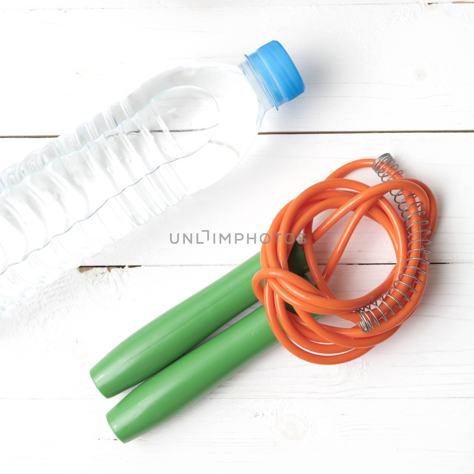 fitness equipment :jumping rope and water bottle on white wood table