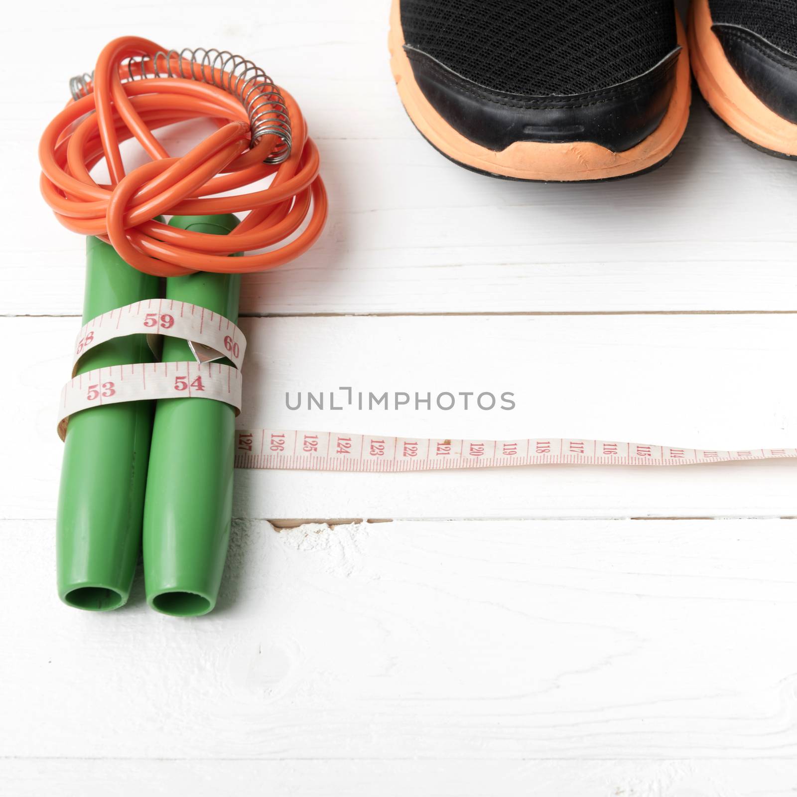 fitness equipment : running shoes,jumping rope and measuring tape on white wood table