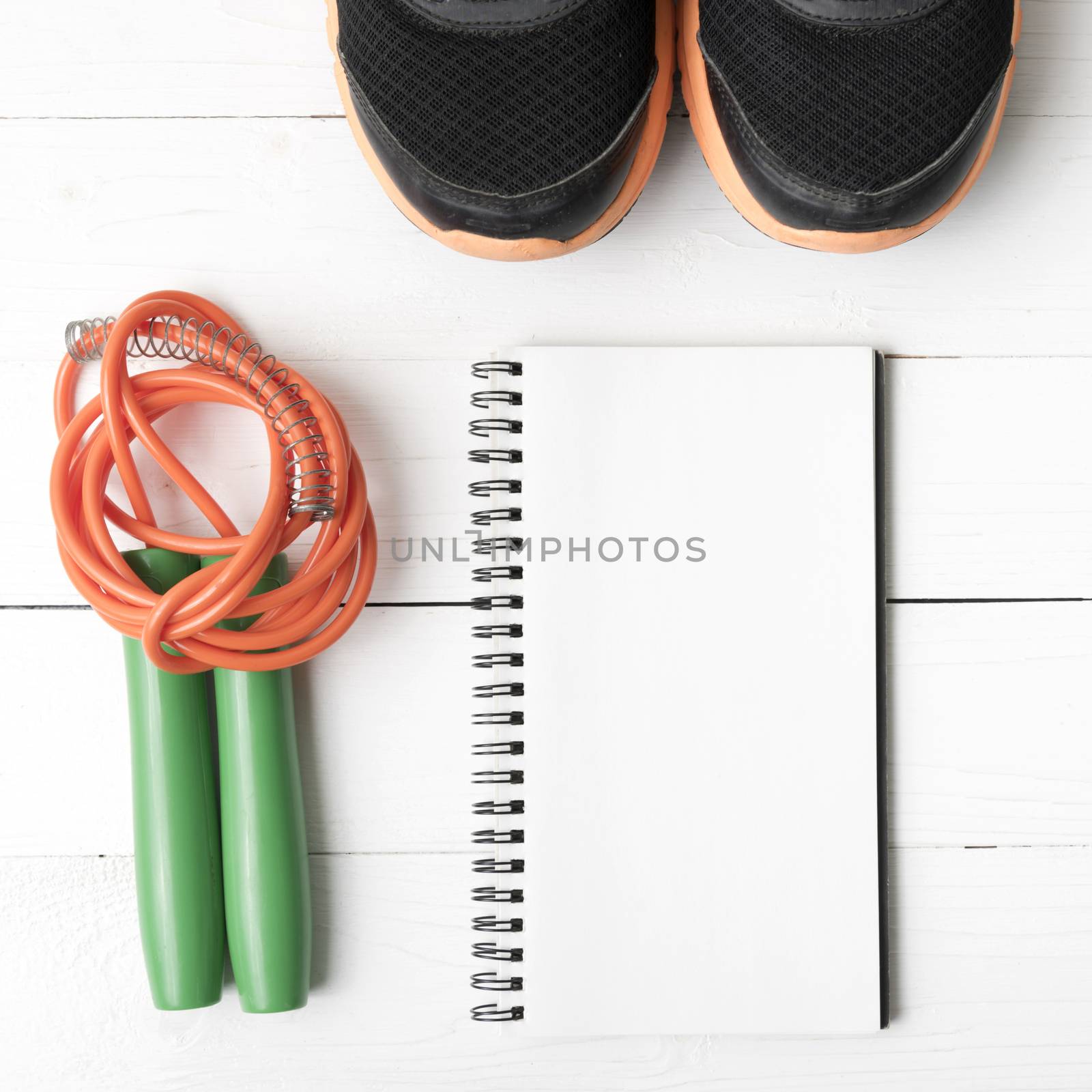 fitness equipment : running shoes,jumping rope and notepad on white wood table