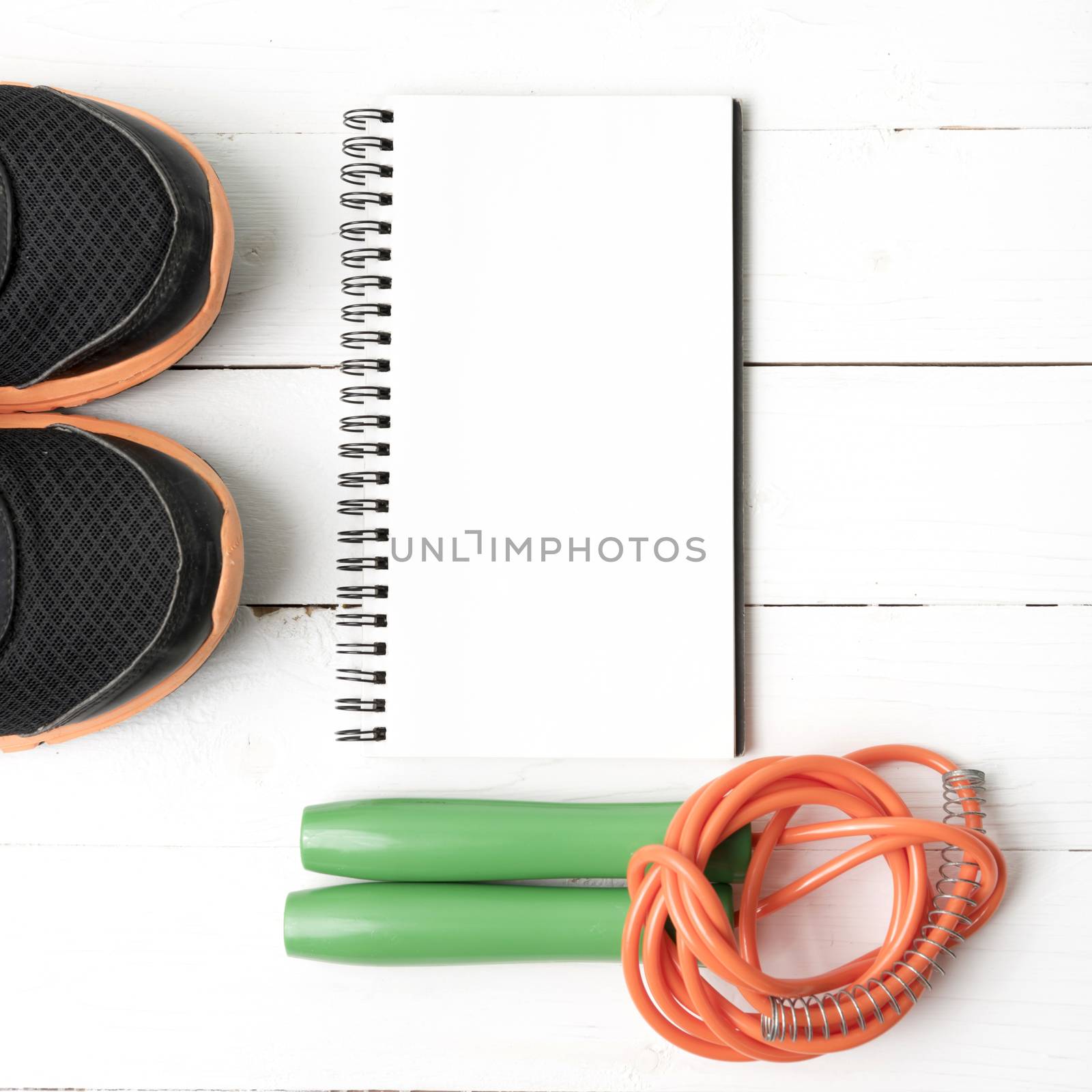 fitness equipment : running shoes,jumping rope and notepad on white wood table