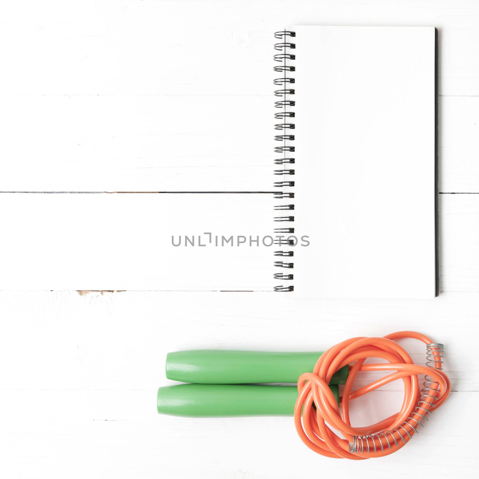 fitness equipment : jumping rope and notepad on white wood table