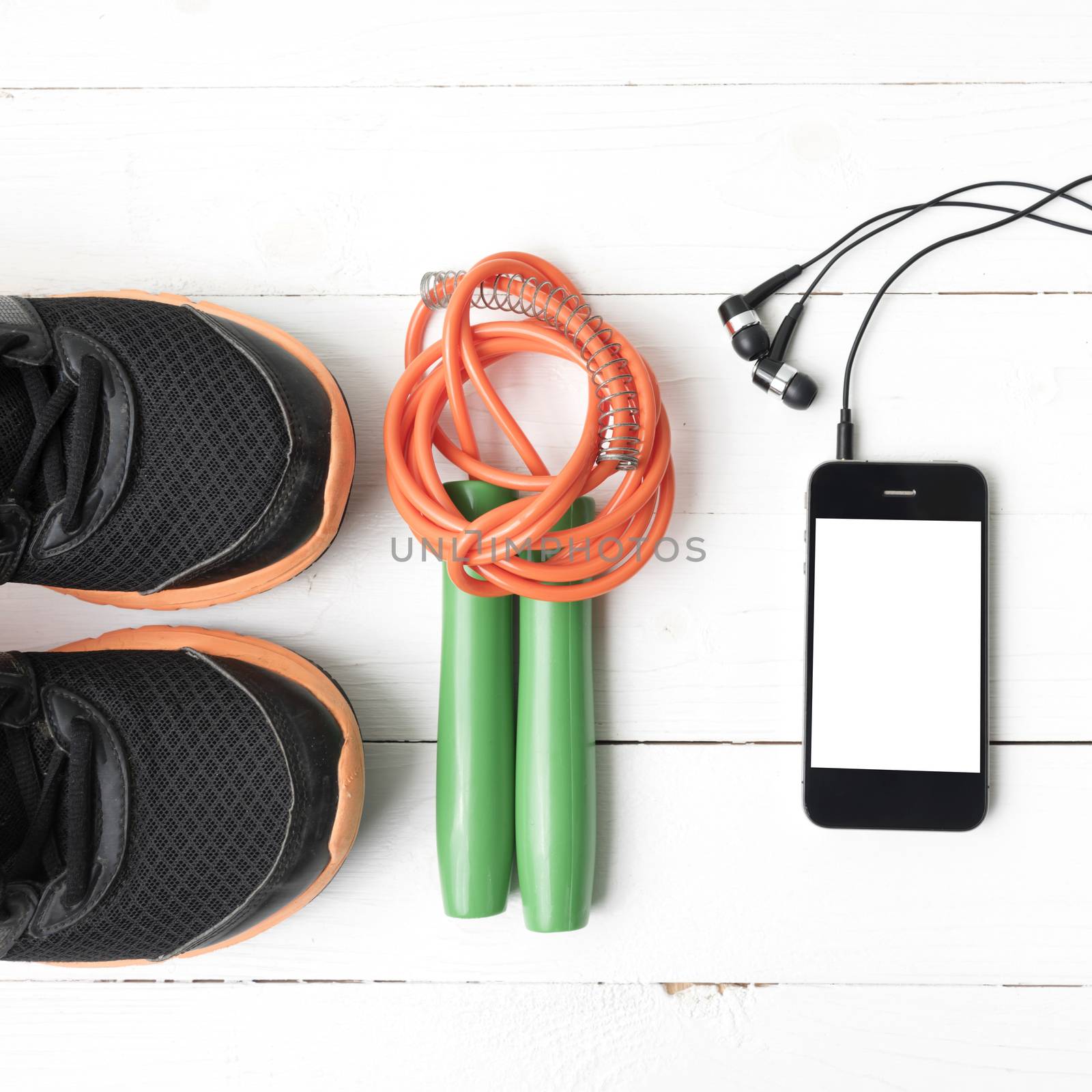 fitness equipment : running shoes,jumping rope and phone on white wood table