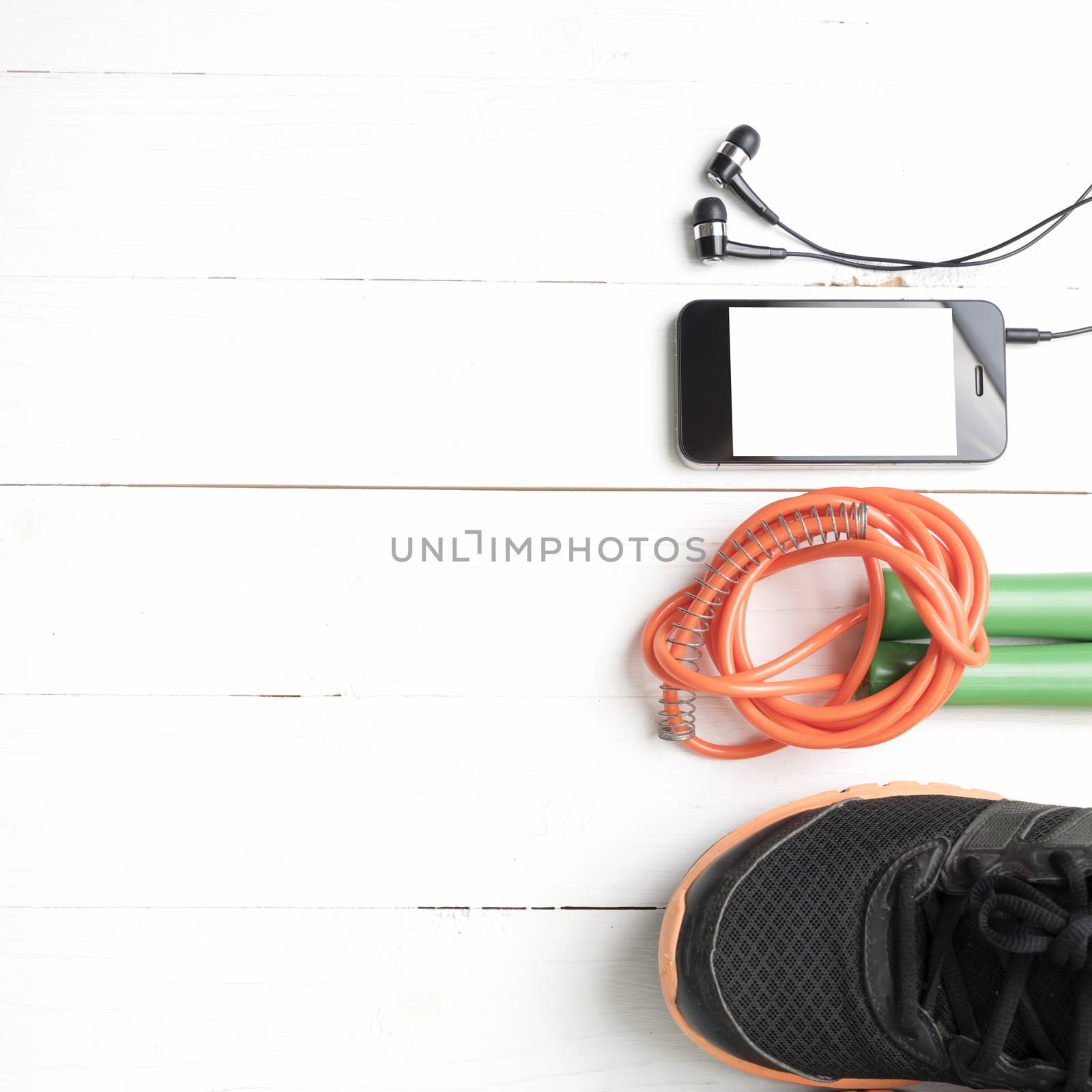 fitness equipment : running shoes,jumping rope and phone on white wood table