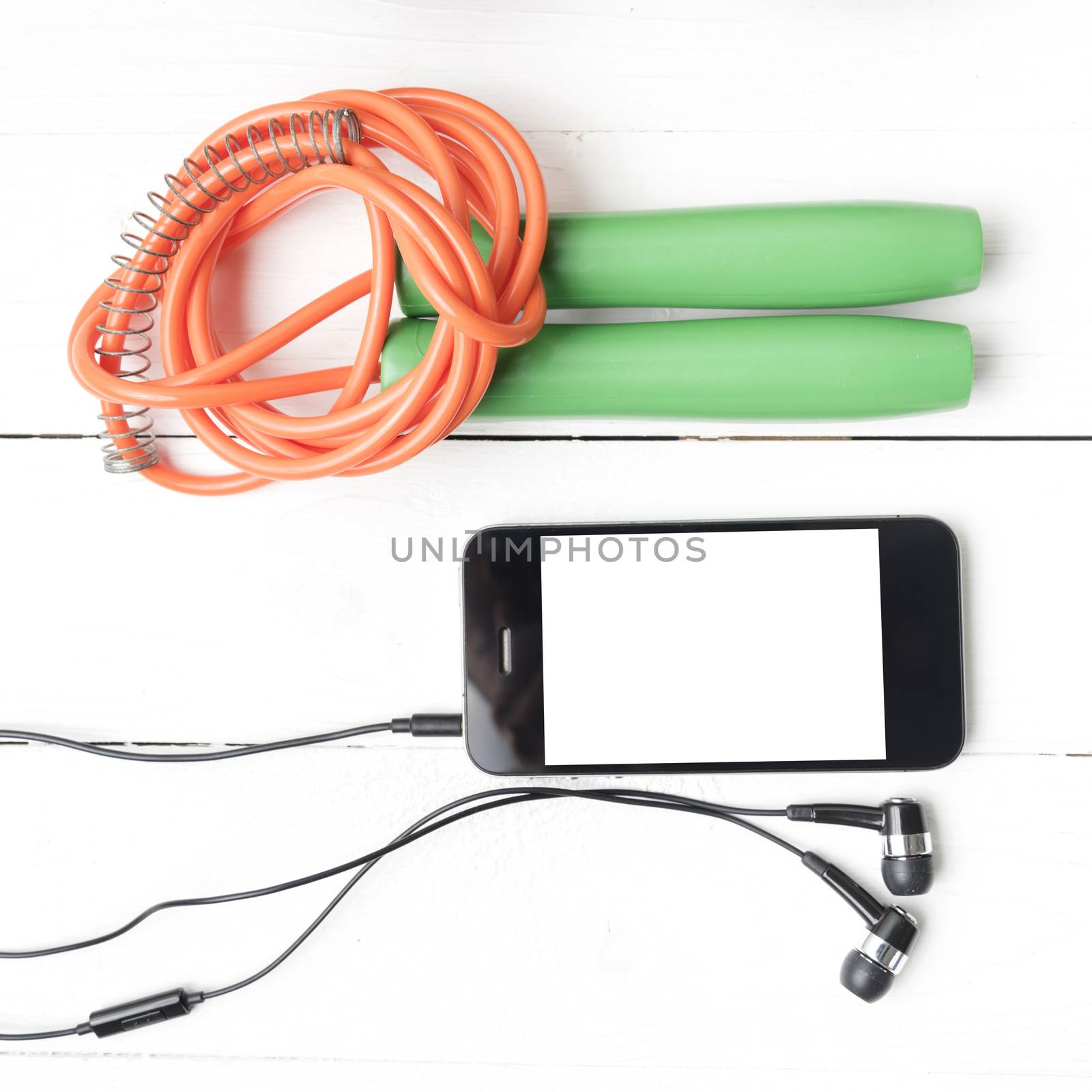 fitness equipment : jumping rope and phone on white wood table