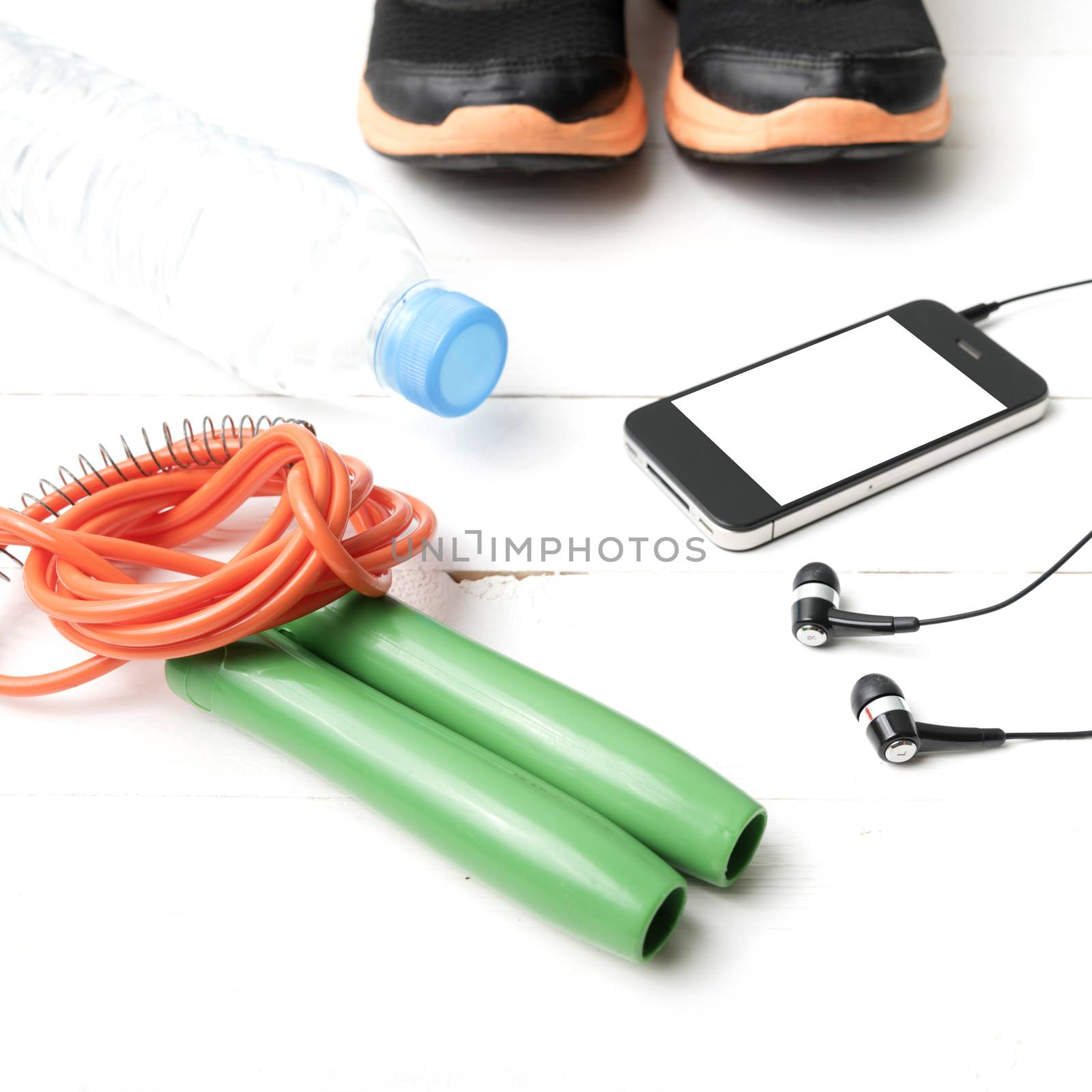 fitness equipment : running shoes,jumping rope,phone and water bottle on white wood table