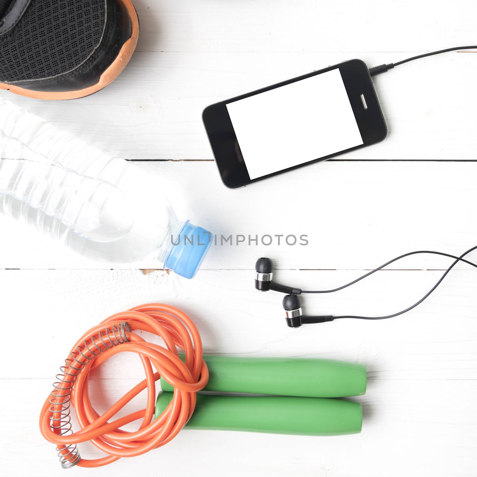 fitness equipment : running shoes,jumping rope,phone and water bottle on white wood table