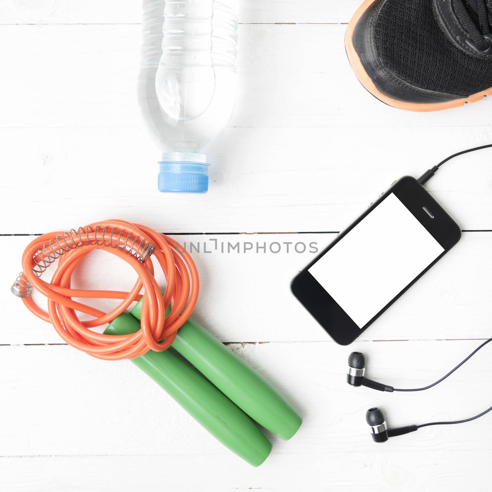 fitness equipment : running shoes,jumping rope,phone and water bottle on white wood table