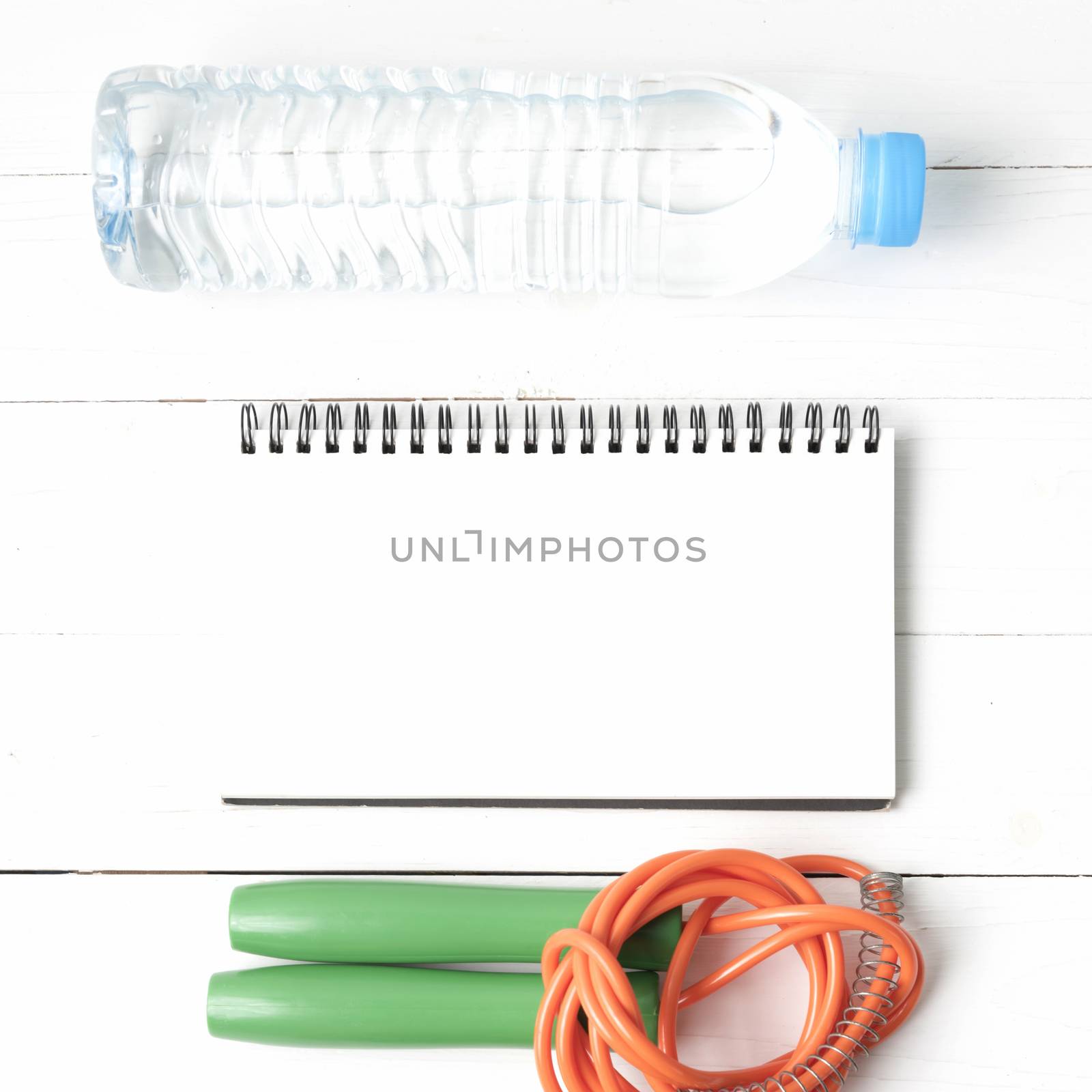 fitness equipment : jumping rope,drinking water and notepad on white wood table