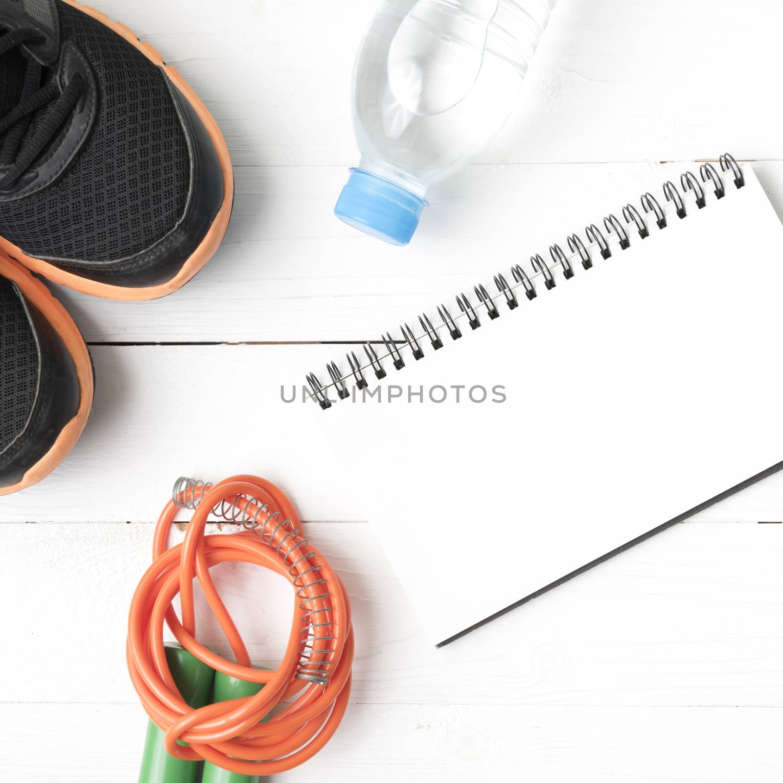 fitness equipment : running shoes,jumping rope,drinking water and notepad on white wood table