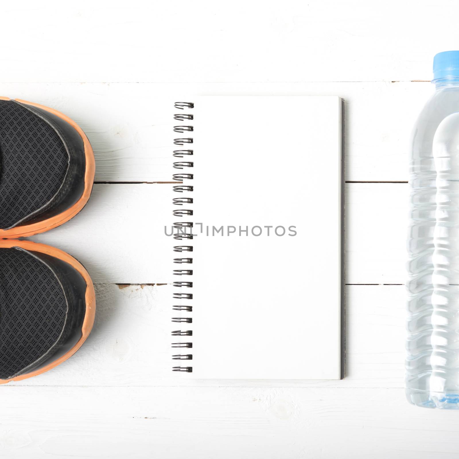 fitness equipment : running shoes,drinking water and notebook on white wood table