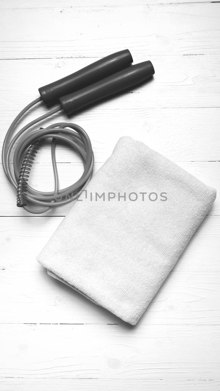 fitness equipment:white towel,jumping rope on white wood table black and white color style