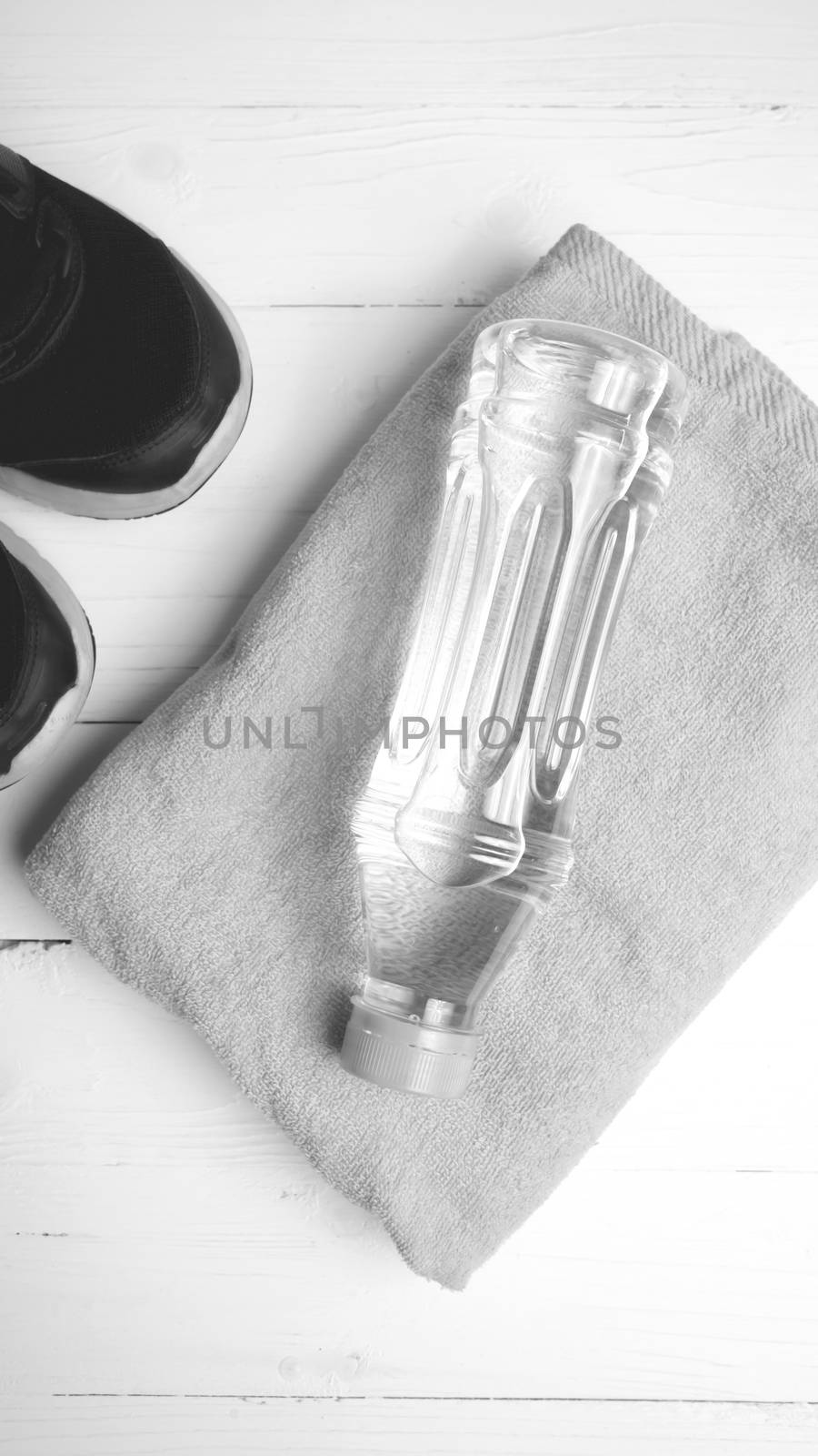 fitness equipment: towel,drinking water and running shoes on white wood table black and white color style