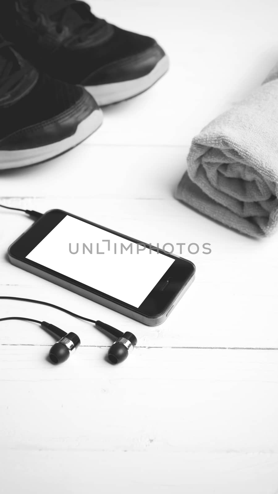 fitness equipment:running shoes,towel and smart phone on white wood table black and white color style