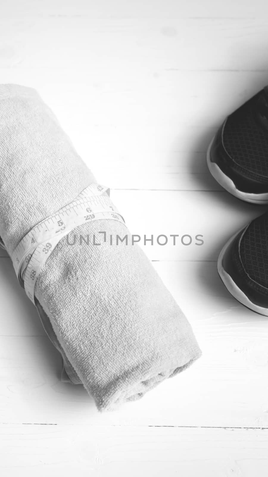 fitness equipment : running shoes,towel and measuring tape on white wood table black and white color style