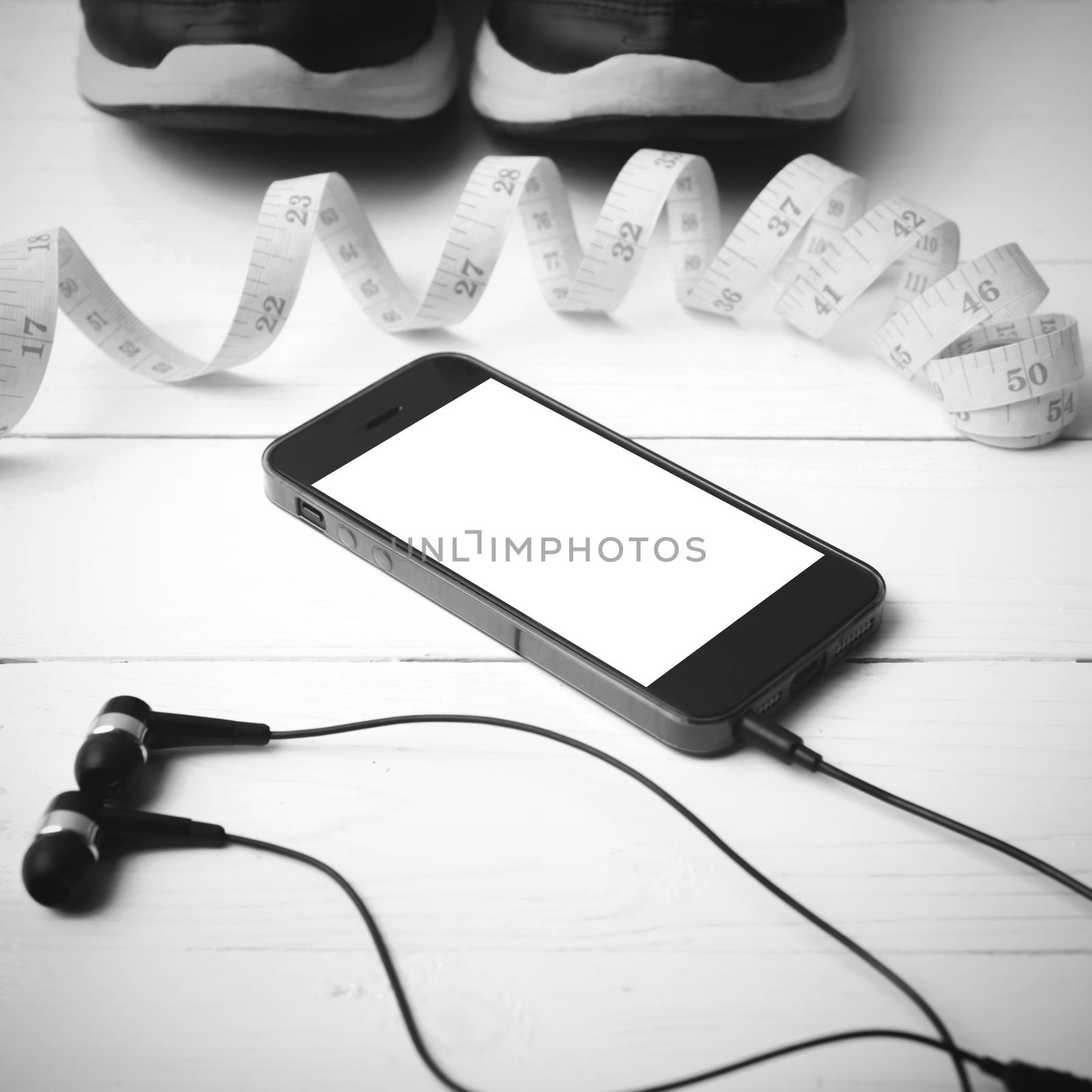 running shoes,measuring tape and phone on white wood table black and white tone color style