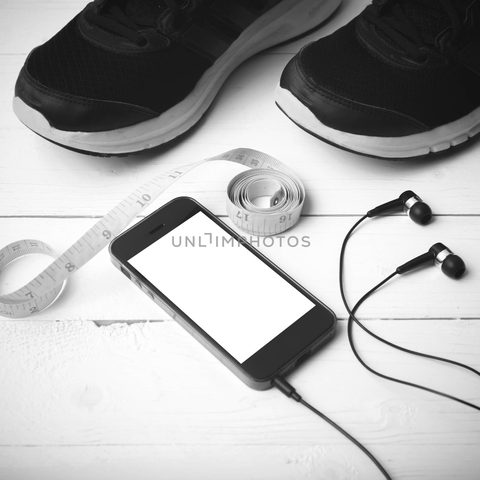 running shoes,measuring tape and phone on white wood table black and white tone color style