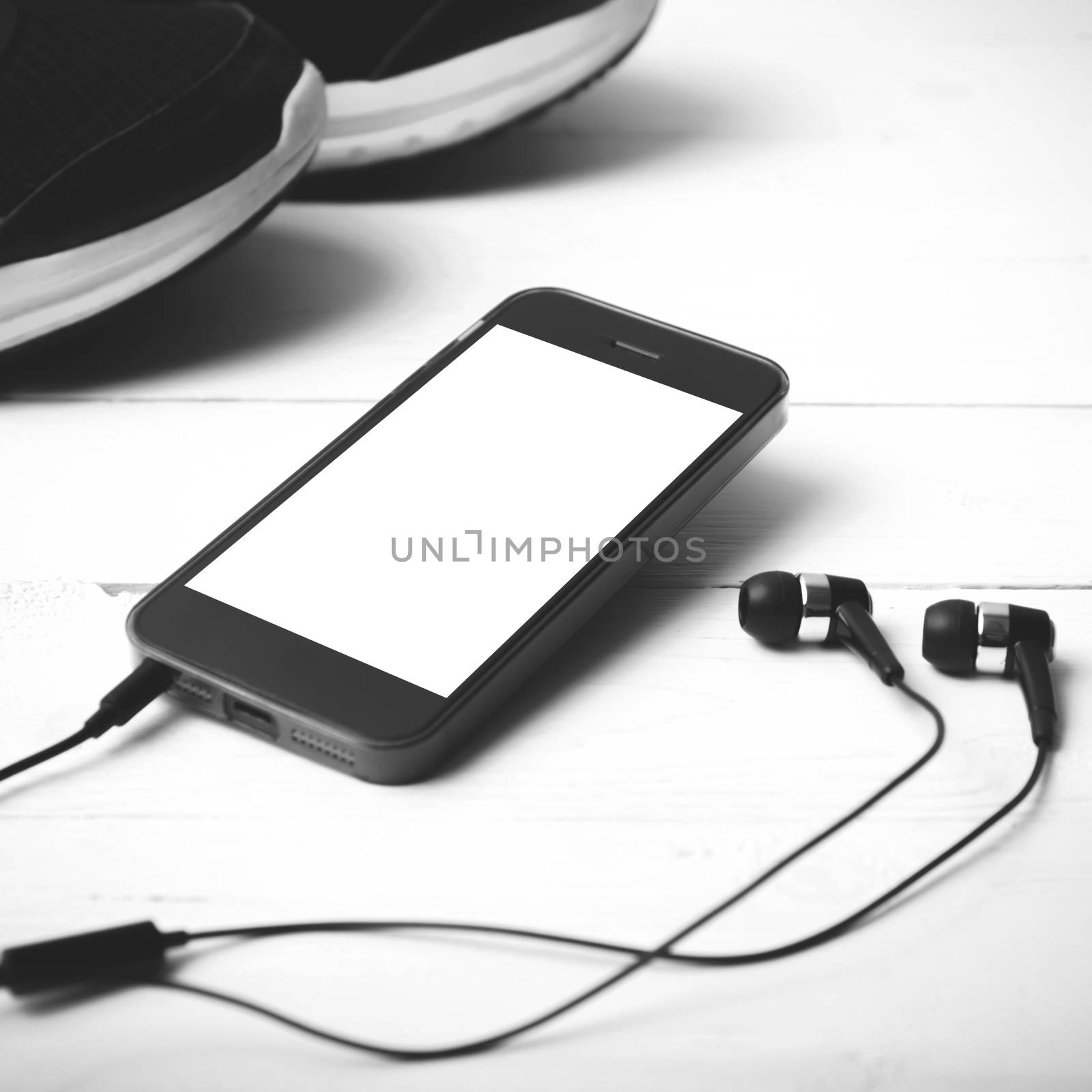 running shoes and phone on white wood table black and white tone color style