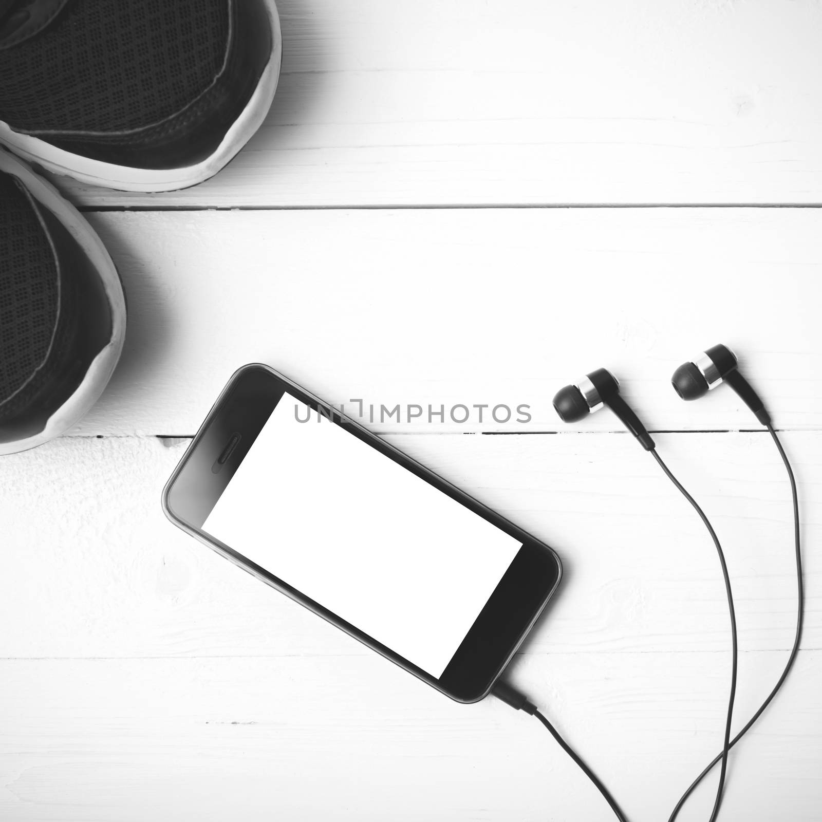 running shoes and phone on white wood table black and white tone color style