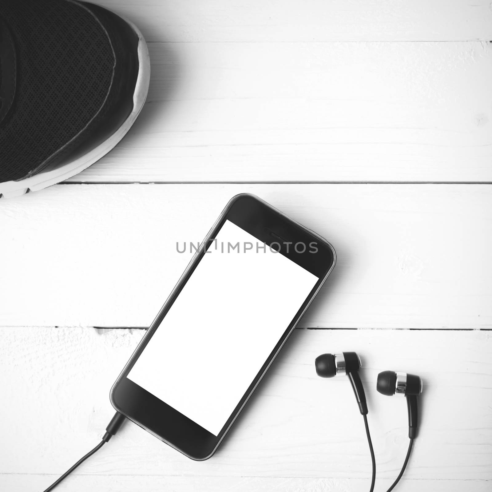 running shoes and phone on white wood table black and white tone color style