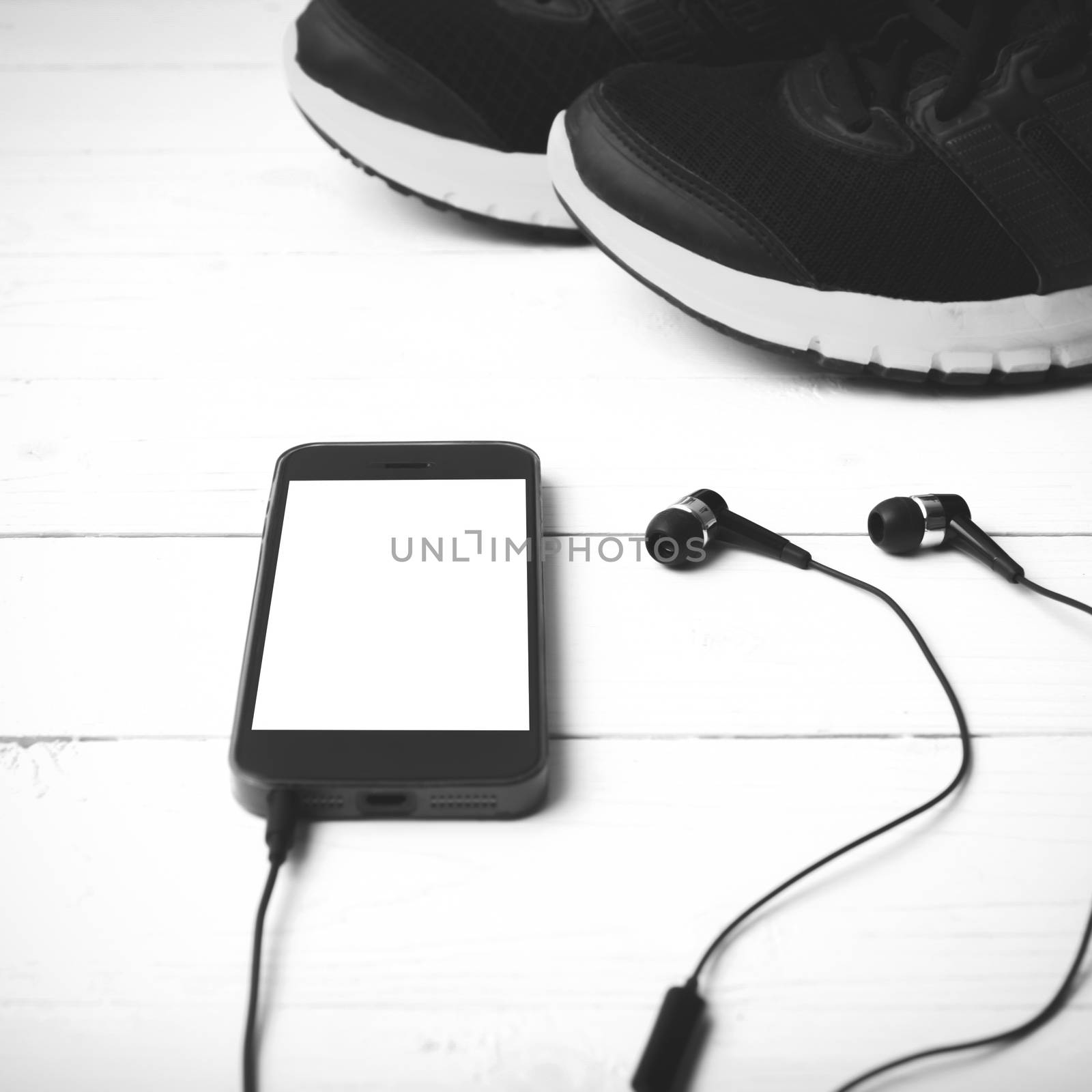 running shoes and phone on white wood table black and white tone color style