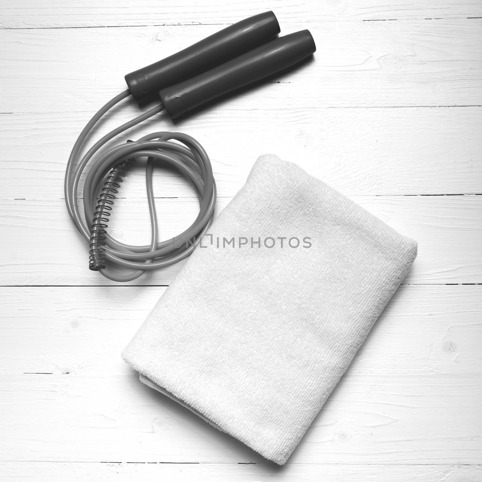 fitness equipment:white towel,jumping rope on white wood table black and white color style