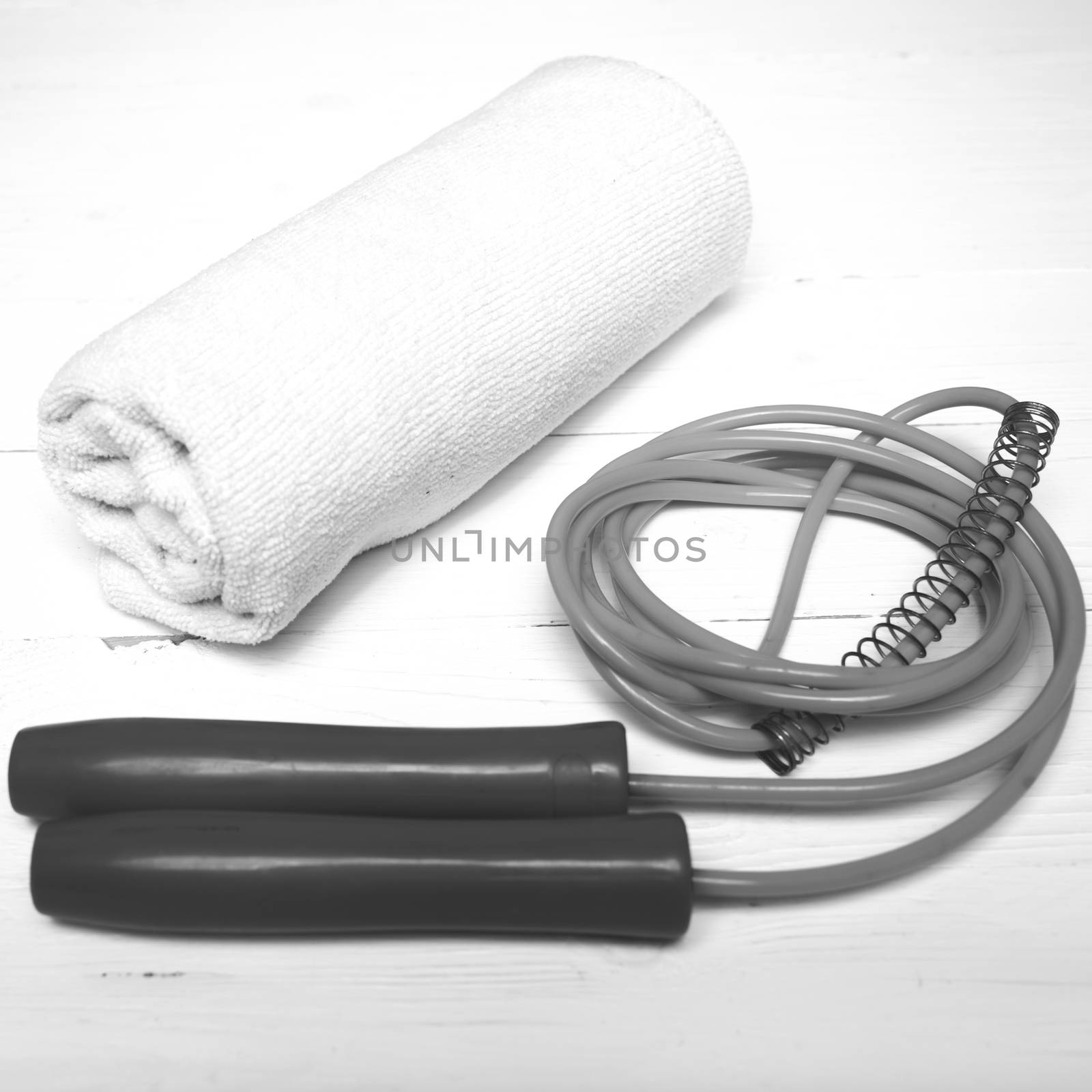 fitness equipment:white towel,jumping rope on white wood table black and white color style