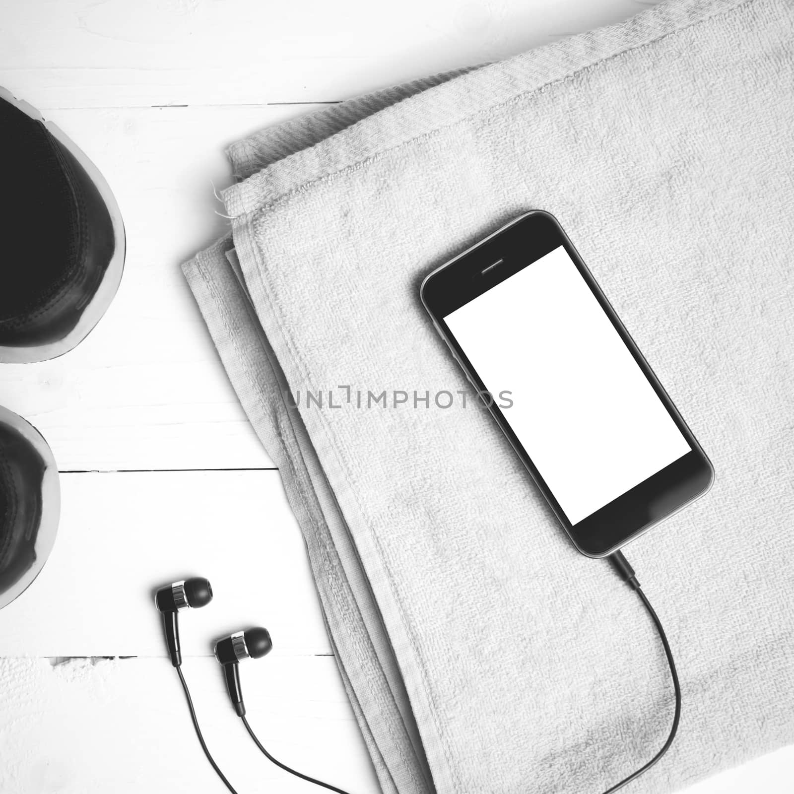 fitness equipment:running shoes,towel and smart phone on white wood table black and white color style