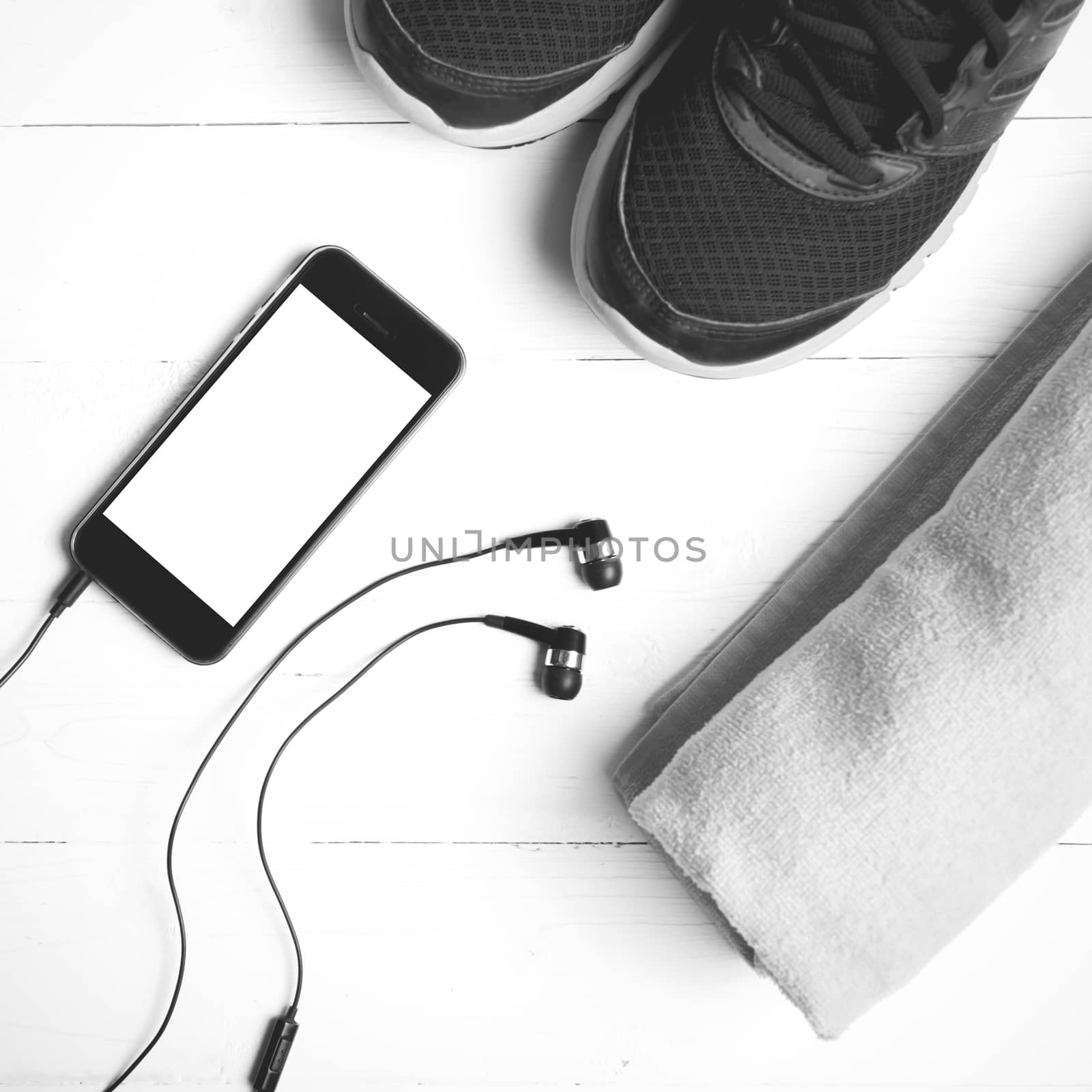 fitness equipment:running shoes,towel and smart phone on white wood table black and white color style