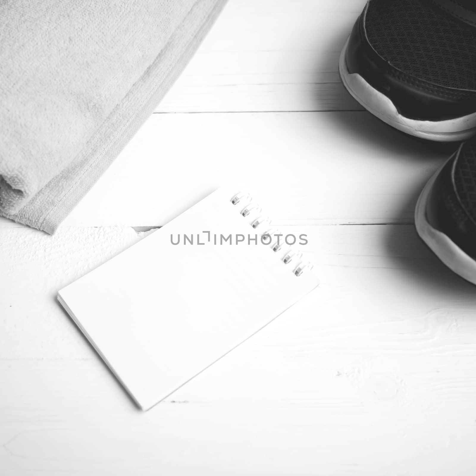 fitness equipment : running shoes,towel and notepad on white wood table black and white color style