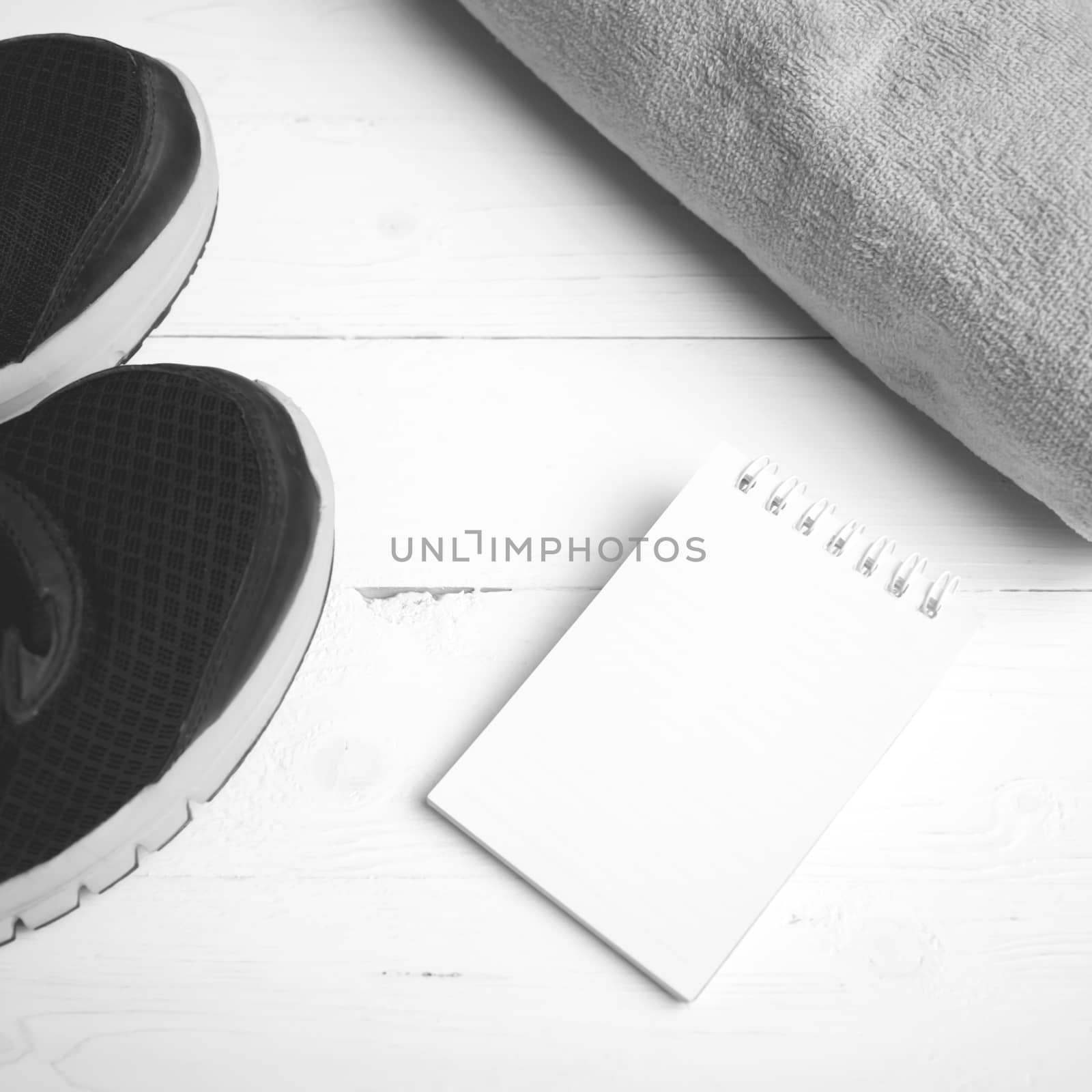 fitness equipment : running shoes,towel and notepad on white wood table black and white color style