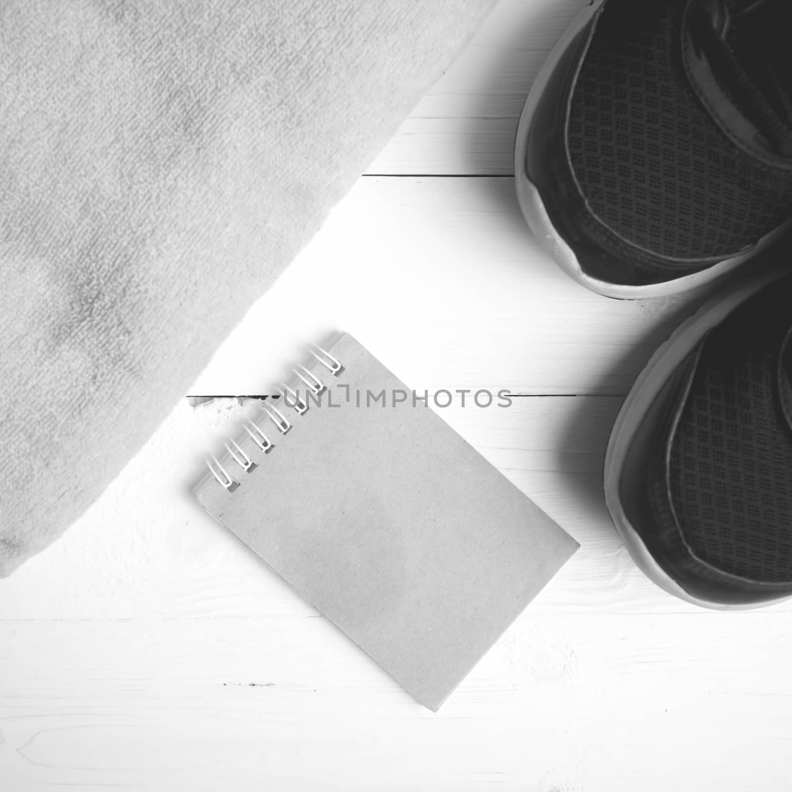 fitness equipment : running shoes,towel and notepad on white wood table black and white color style