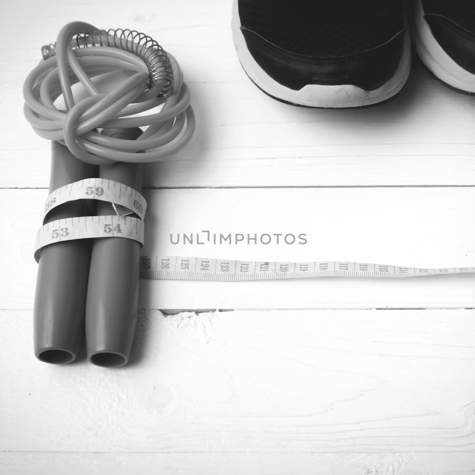 fitness equipment : running shoes,jumping rope and measuring tape on white wood table black and white color tone style