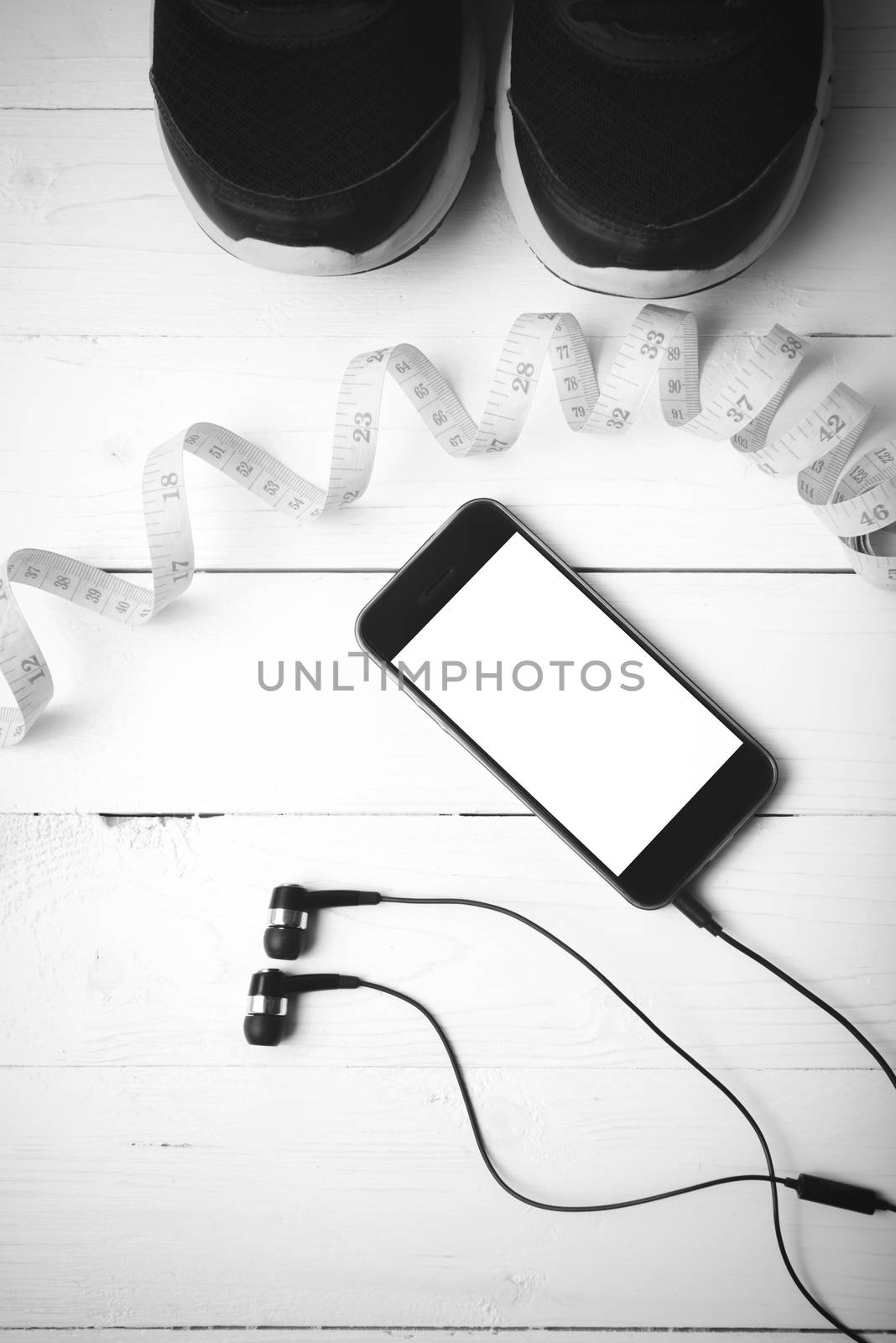 running shoes,measuring tape and phone on white wood table black and white tone color style