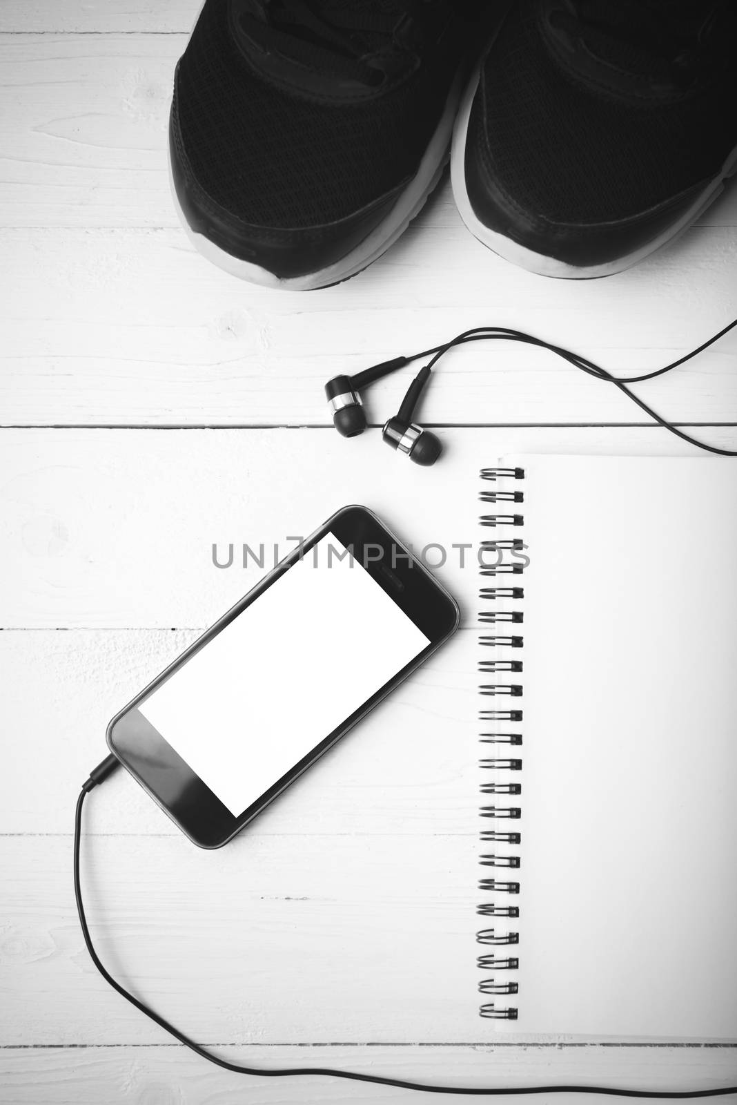 running shoes,notebook and phone on white wood table black and white tone color style