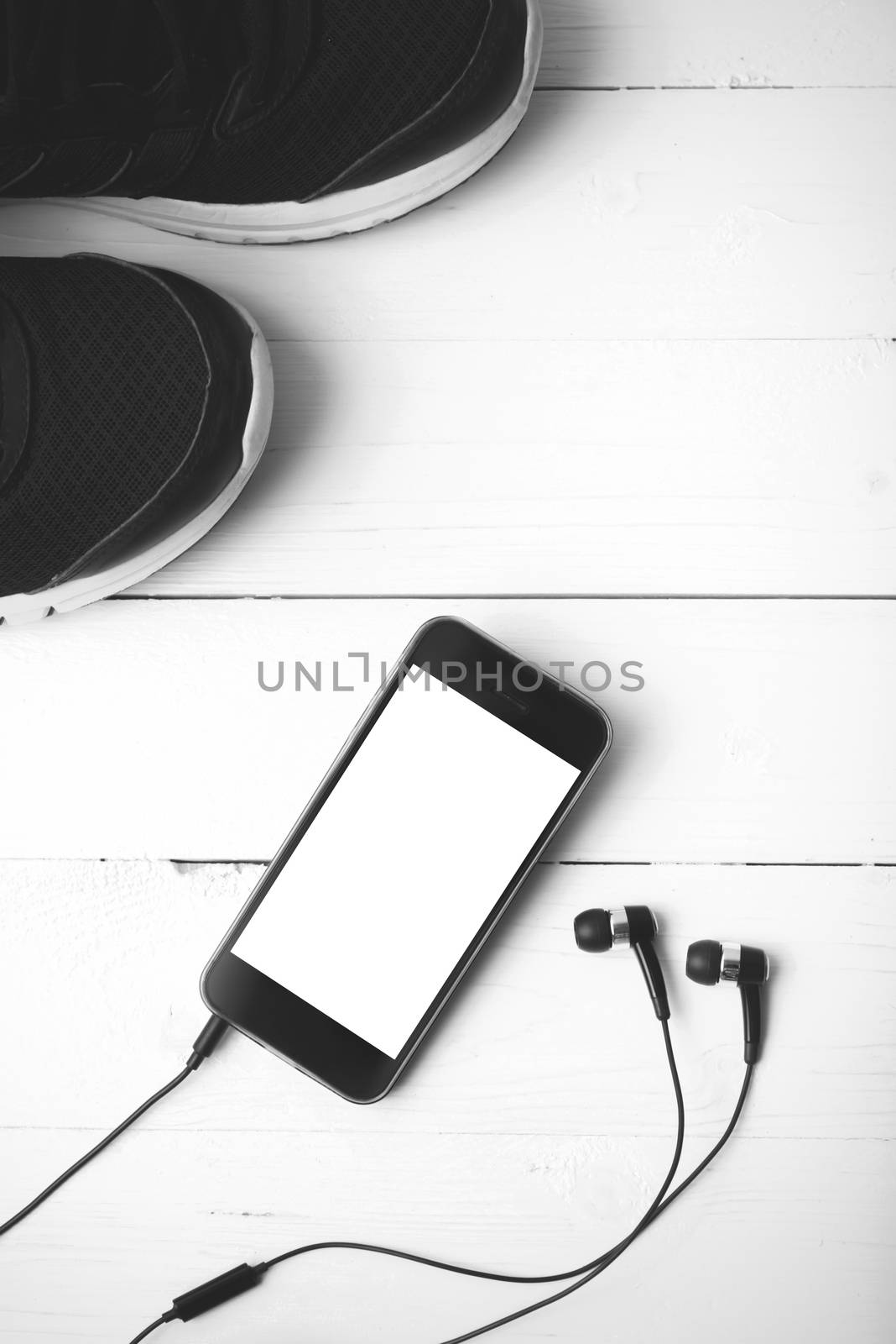 running shoes and phone on white wood table black and white tone color style