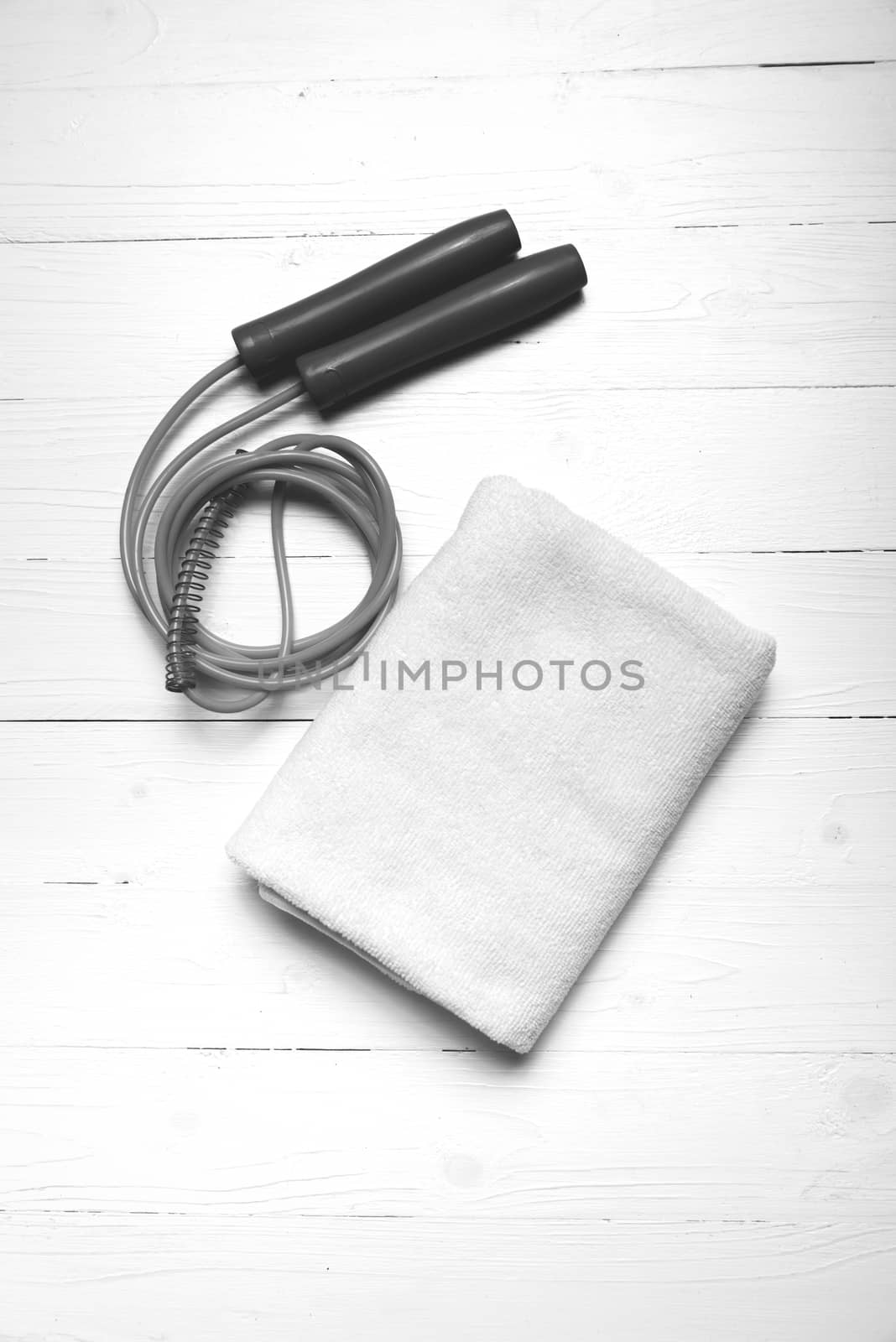 fitness equipment:white towel,jumping rope on white wood table black and white color style