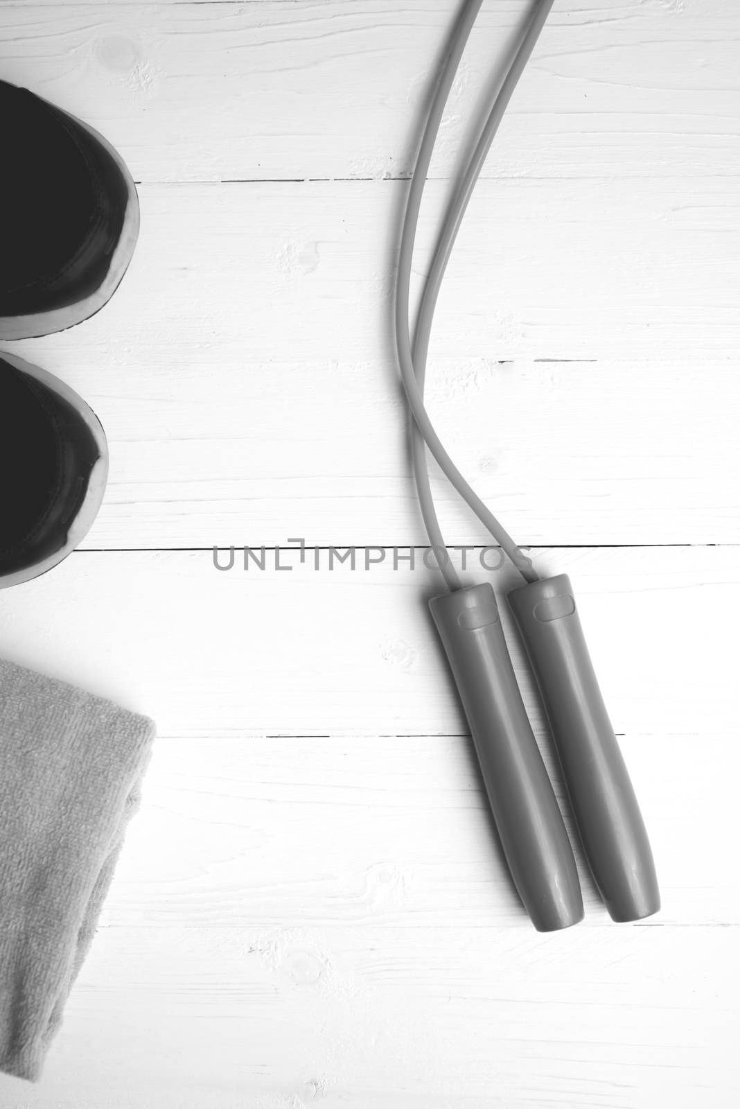 fitness equipment: towel,jumping rope and running shoes on white wood table black and white color style